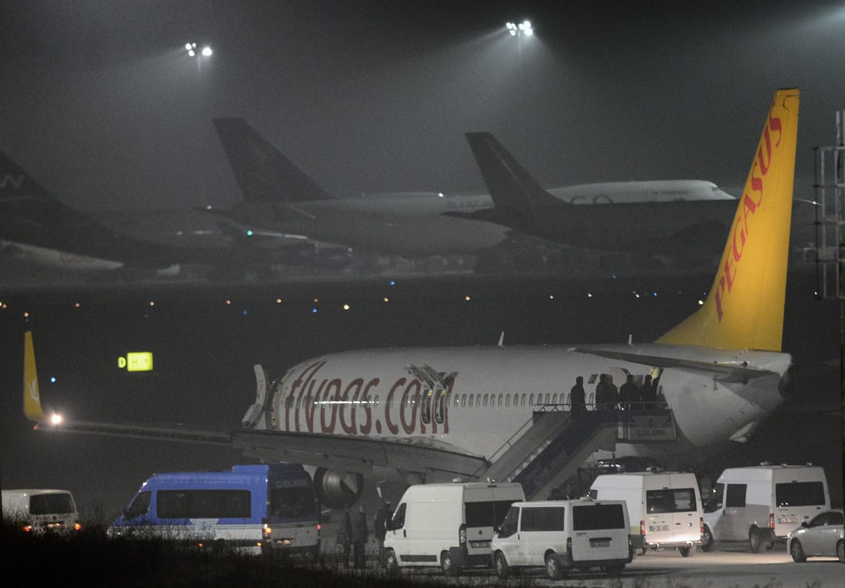 Turkish security officials enter the private Turkish company Pegasus plane before they evacuate passengers at the Sabiha Gokcen Airport in Istanbul, Turkey, Friday, Feb. 7, 2014. An official says authorities have subdued a man who attempted to hijack a Turkish plane to Sochi, Russia, and that the other passengers have been evacuated.