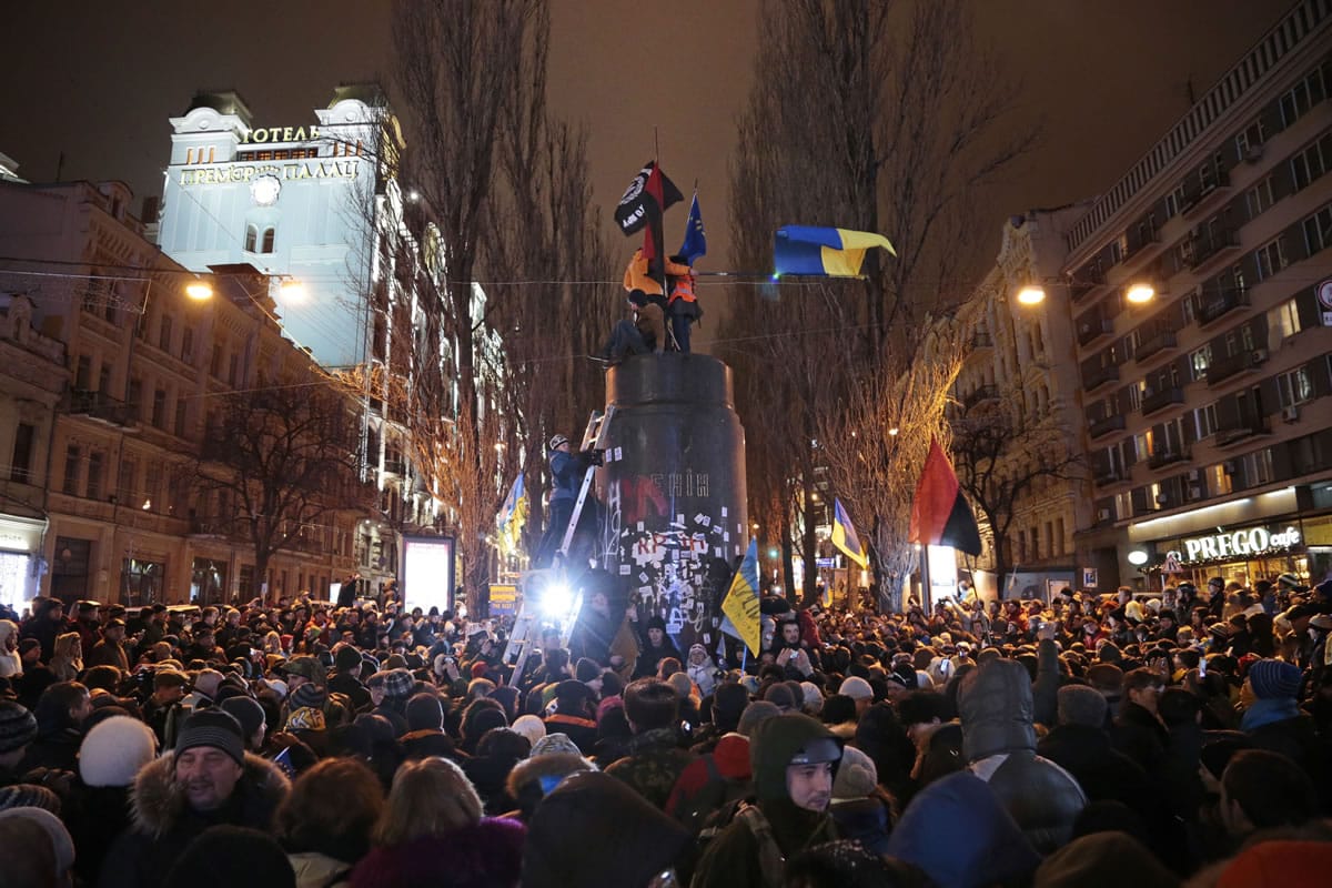 Ukrainian protesters stand atop the monument Sunday after the statue of Vladimir Lenin was toppled by protesters in Kiev, Ukraine.