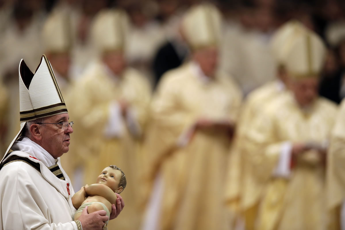 Pope Francis carries a statue of baby Jesus as he celebrates the Christmas Eve Mass on Tuesday in St.