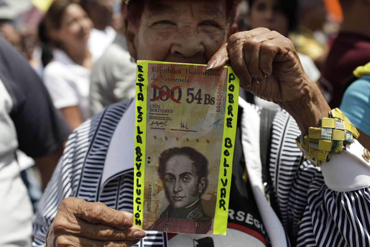 An anti-government protester in Caracas holds up a fake Venezuelan banknote that reads in Spanish, &quot;This is the revolution.