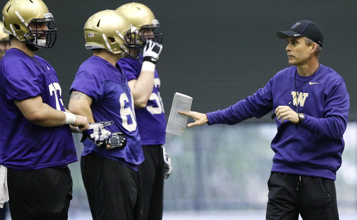 New Washington head football coach Chris Petersen, right, talks to players on the first day of Spring NCAA college football practice, Tuesday, March 4, 2014 in Seattle. (AP Photo/Ted S.