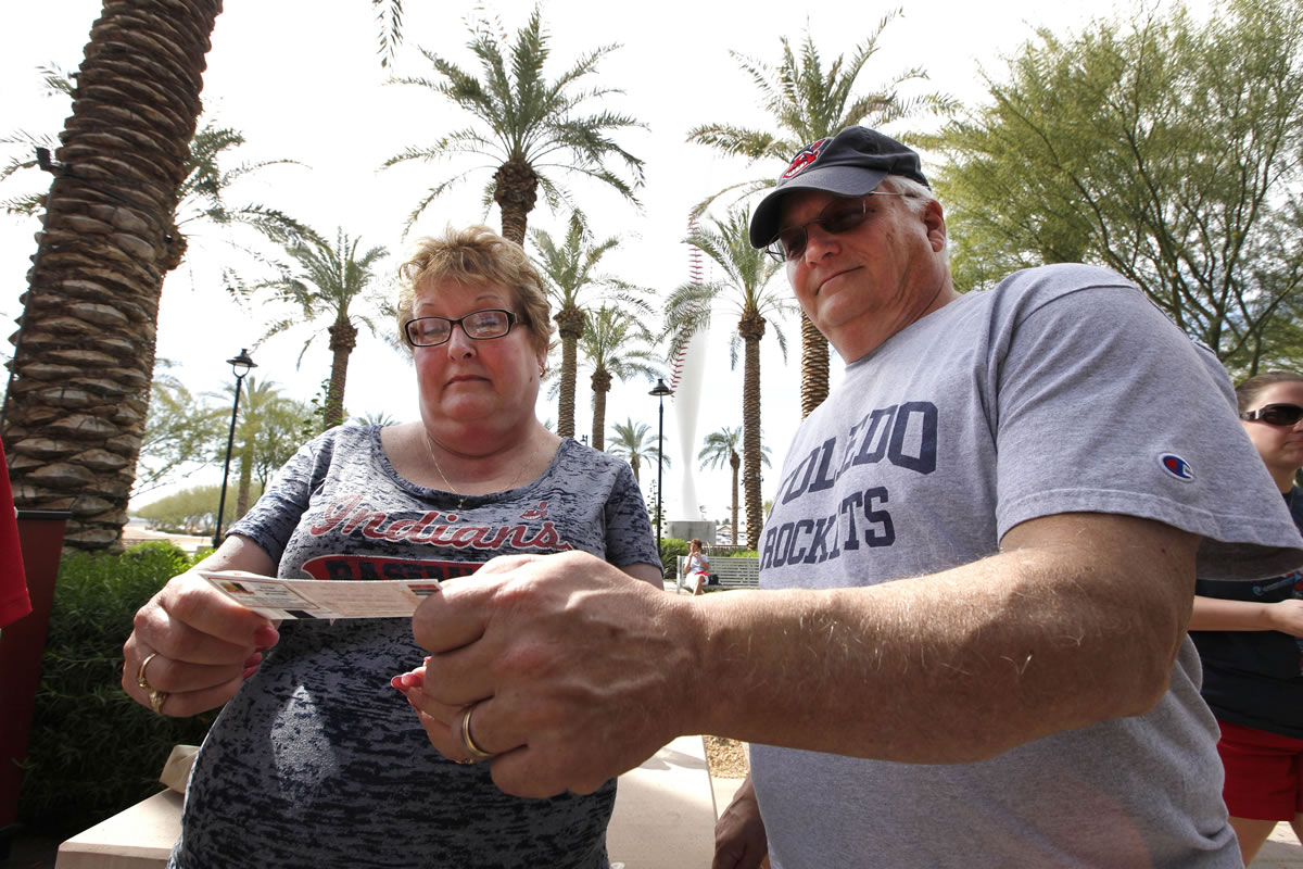 Sue Knieriemen and her brother Charles Bork, both residents of snowy Ohio, check their tickets outside Goodyear Ballpark in Goodyear, Ariz., before an exhibition baseball game between the Cincinnati Reds and the Cleveland Indians.