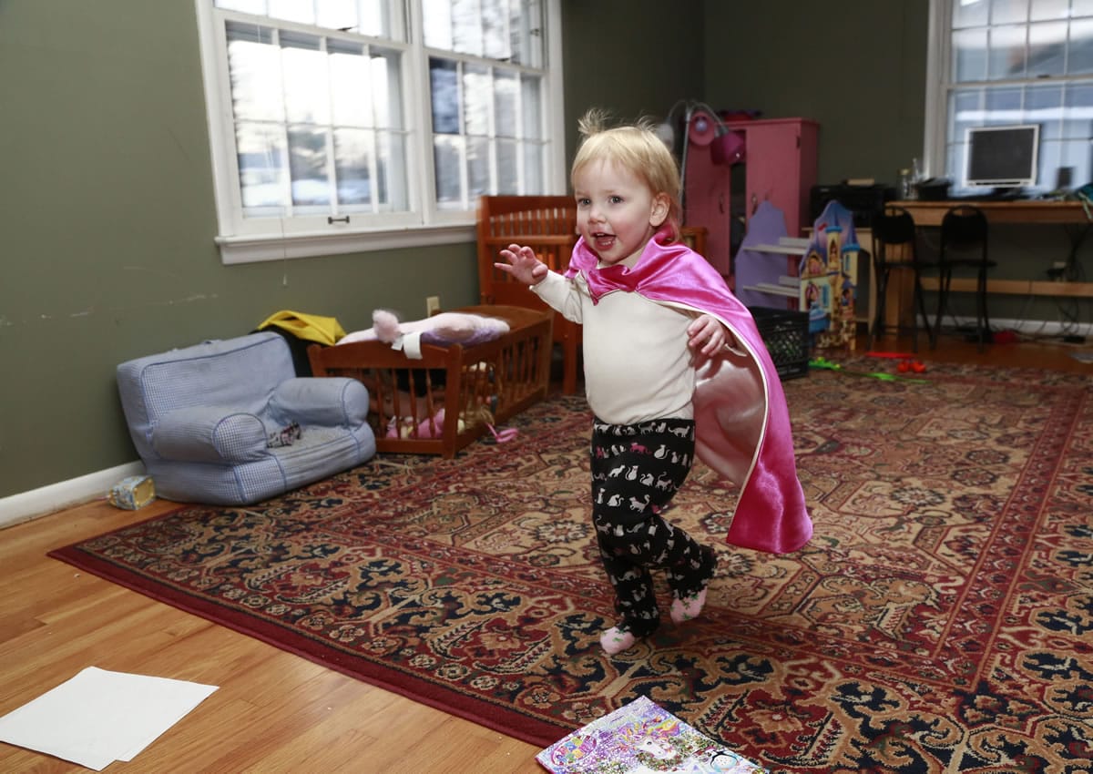 Felicity Beck-Kehoe runs wearing a cape through the family home of her parents, Mike Beck and Joanne Kehoe, as the family tries to combat cabin fever Monday in Indianapolis.