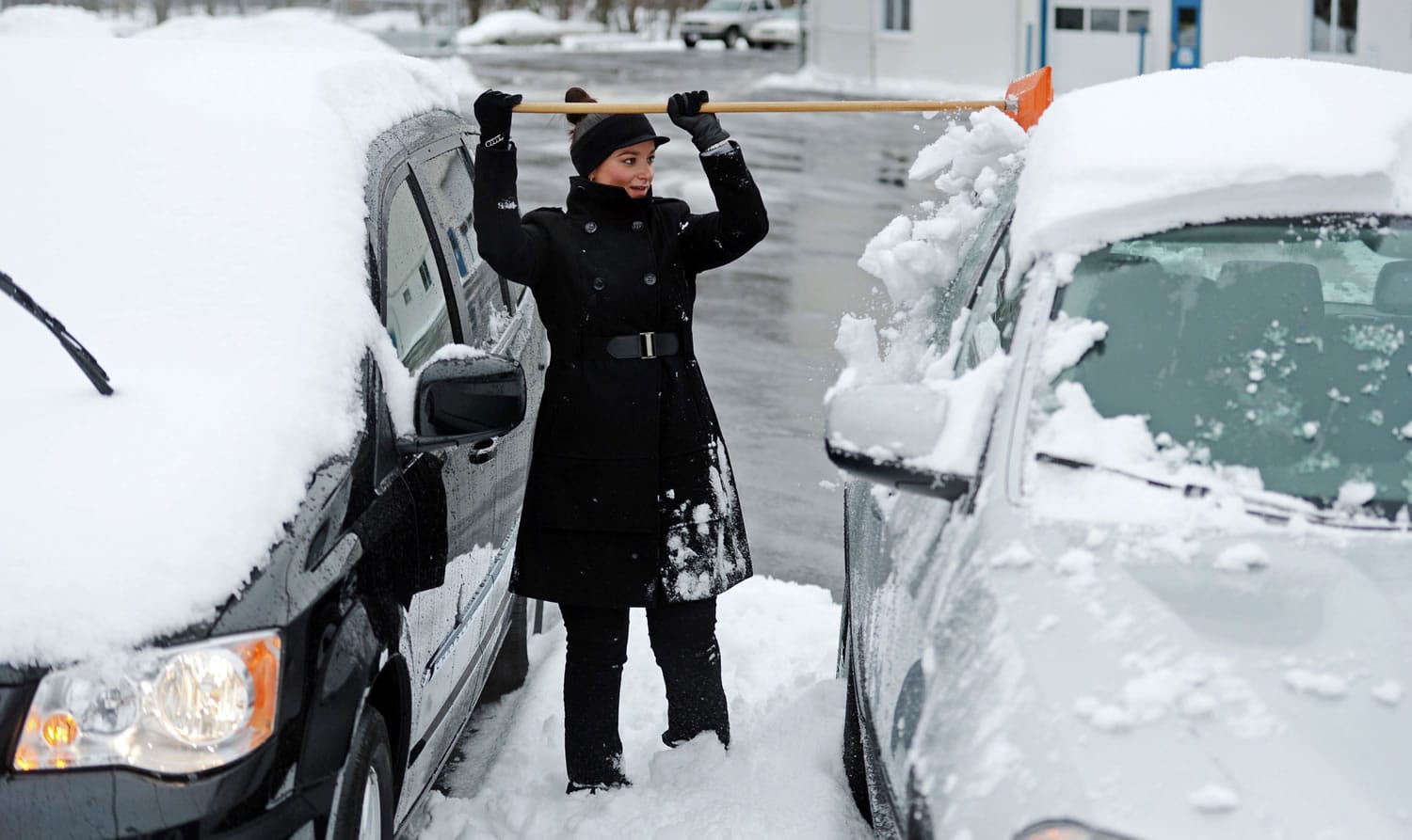 Kamila Pelliccia, a sales consultant at Don Mallon Chevrolet in Norwich, Conn., clears snow off vehicles in the dealership lot Wednesday.