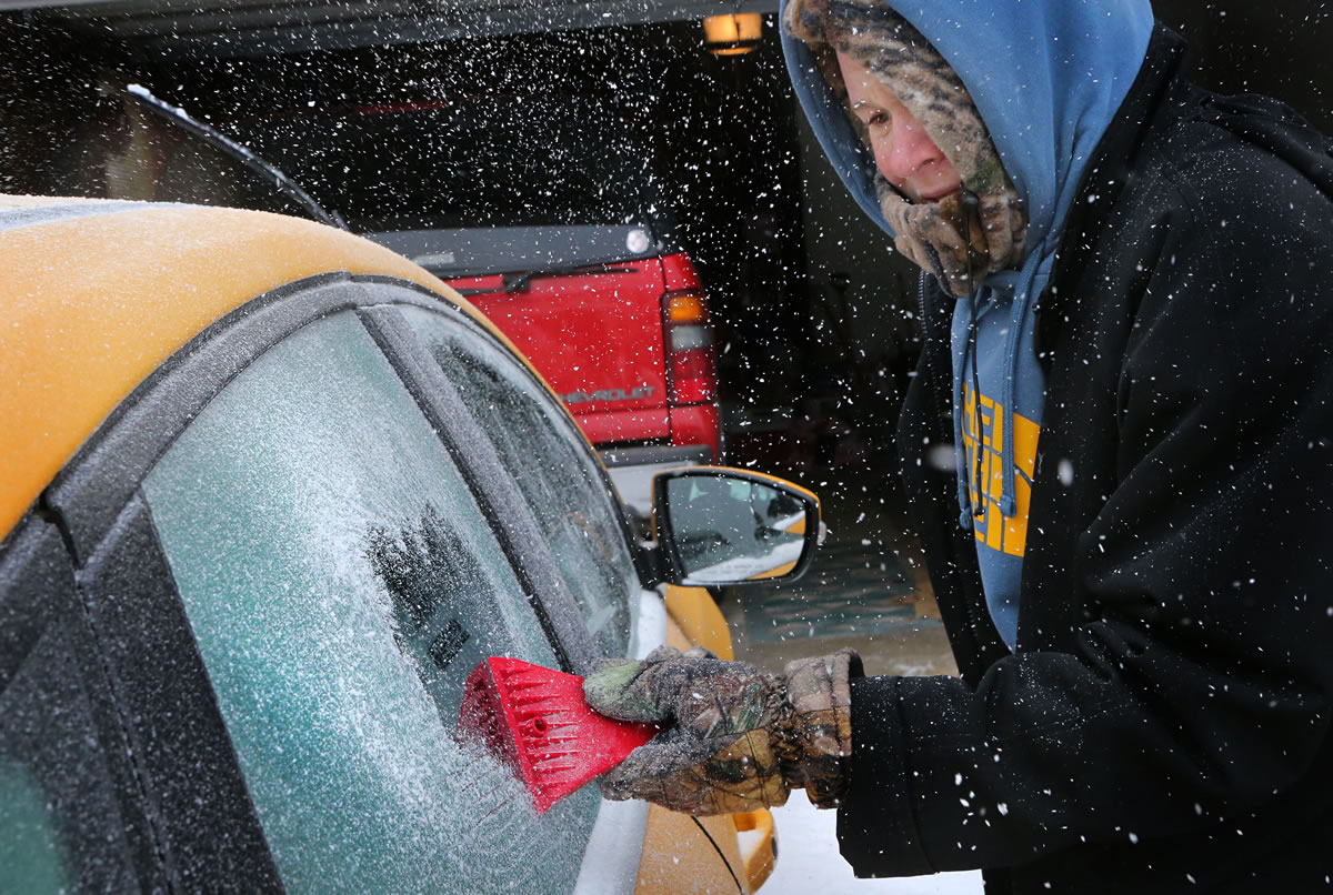 Landon Porter, 15, scrapes the ice off his mother's car outside his home Sunday in St. Charles, Mo.
