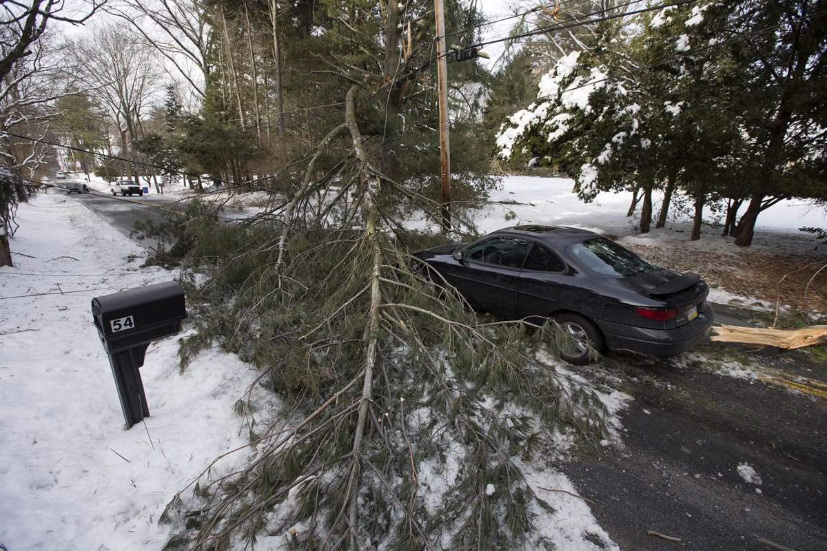 An abandoned car and a tree limb that took out a utility line block a road in the aftermath of a winter storm Thursday in Media, Pa.