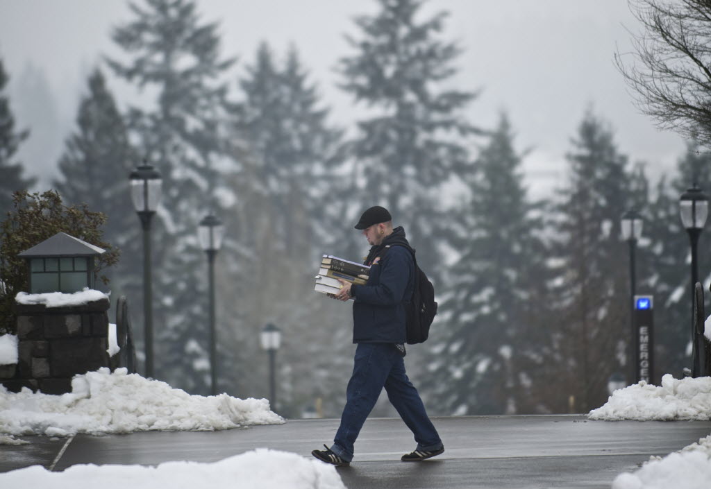 Anthropology major Daniel Radcliffe, 31, carries a stack of book across the Washington State University Vancouver campus Monday. The campus reopened at 11 a.m.