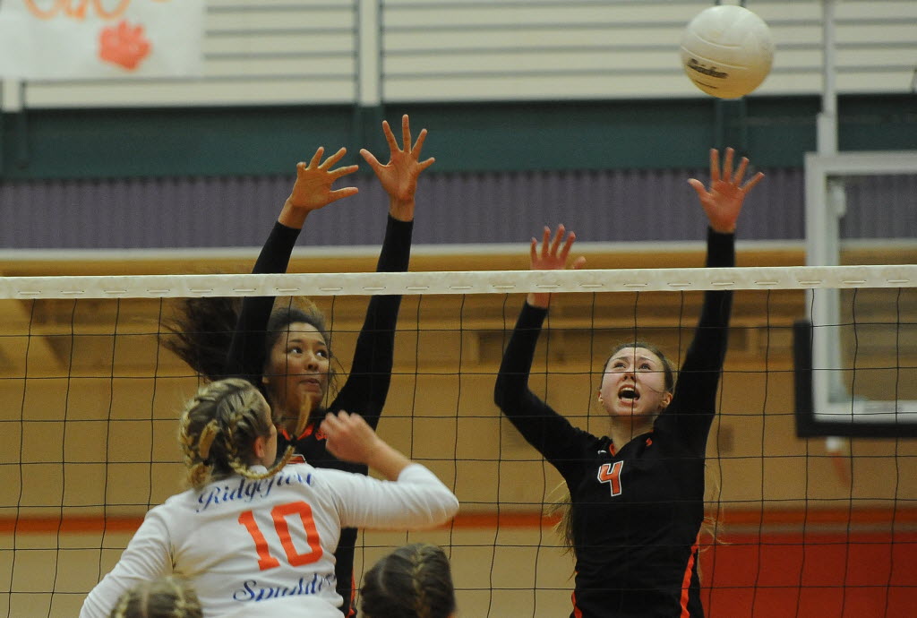 Battle Ground High School's "Lady Tigers" Ashley Watkins (C) and Kimberly Lasley (R) defend the net against Ridgefield's Madi Harter (L) at a volleyball in Battle Ground Thursday September 10, 2015.