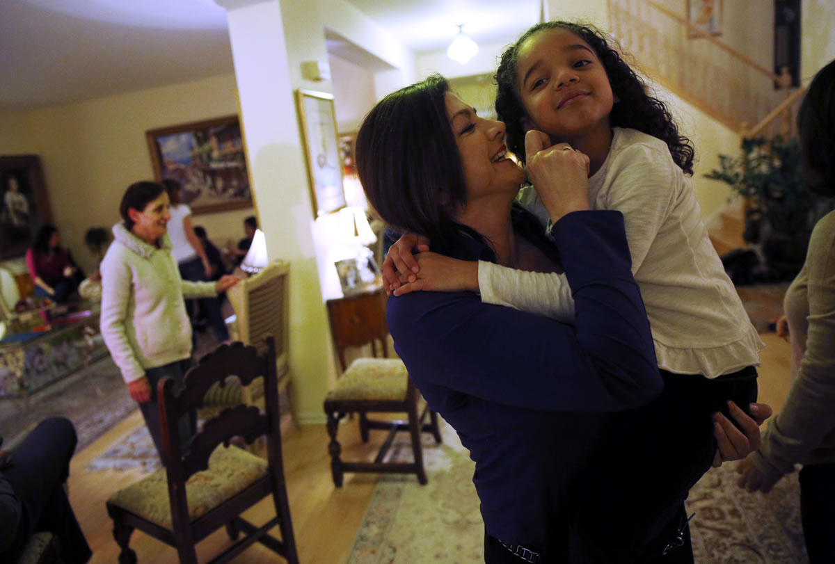 Minoo Panahi holds her niece Isabelle Placide, 5, during a Baha'i devotional in the home of a family member on Jan.