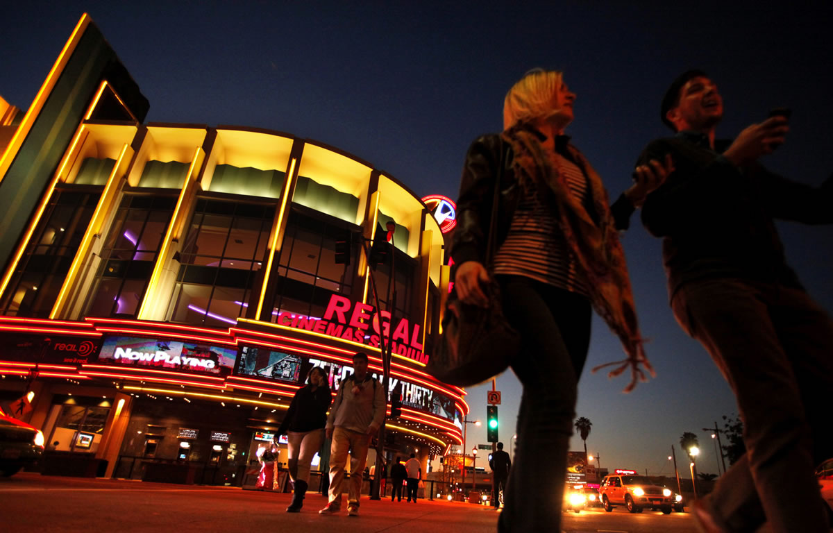 People walk in front of the Regal Cinemas LA Live Stadium 14 in Los Angeles.