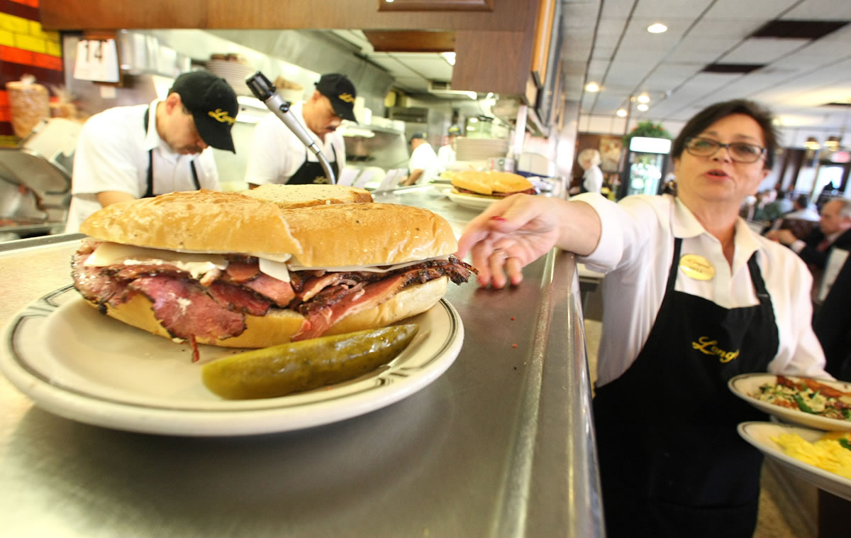 Sheila Abramson, a waitress at Langer's Delicatessen in Los Angeles, reaches out for a plate while serving customers on National Pastrami Day on January 14.