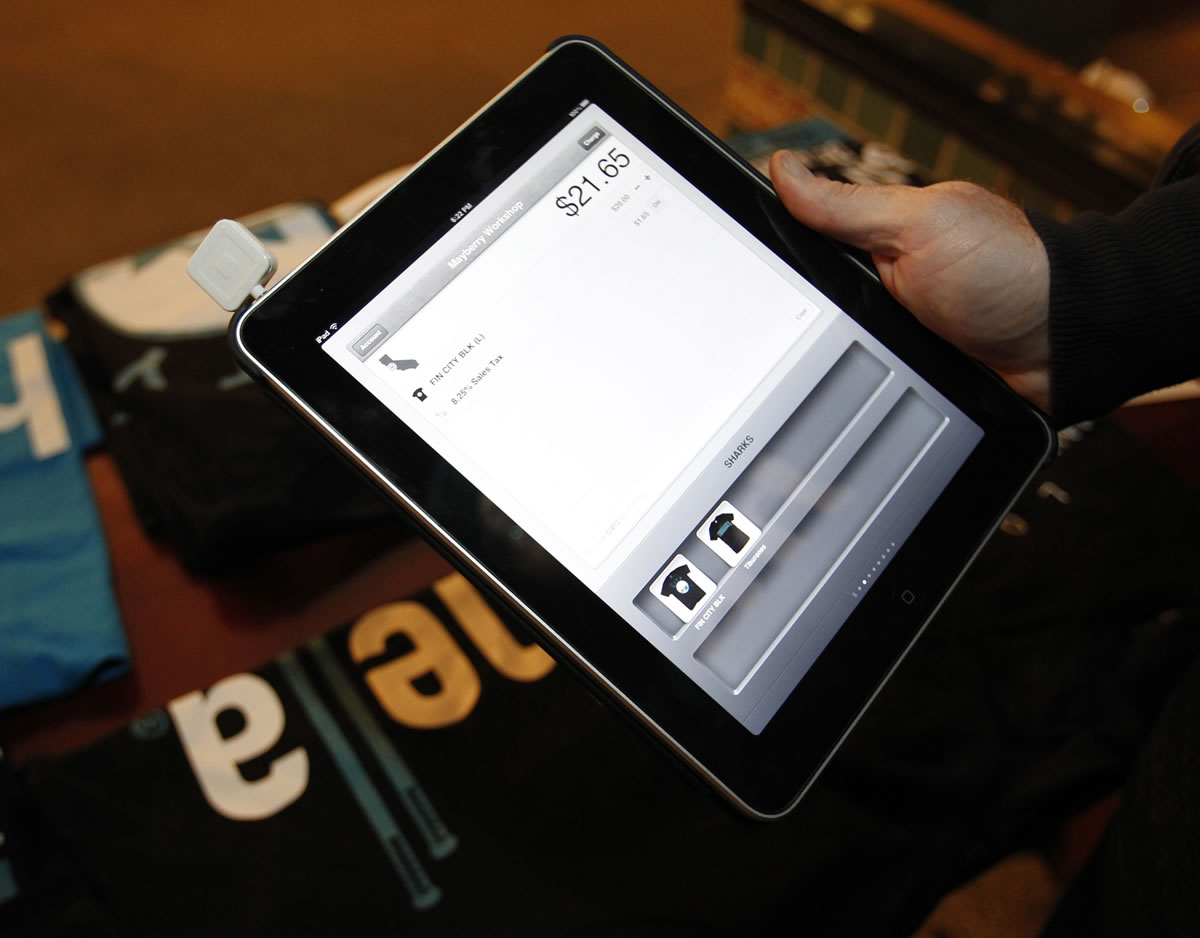 Adam Mayberry, of Mayberry Workshop, shows his iPad with the Square software that allows him to turn his iPad into a cash register in order to sell the company's shirts before a San Jose Sharks game in San Jose, Calif., in December.