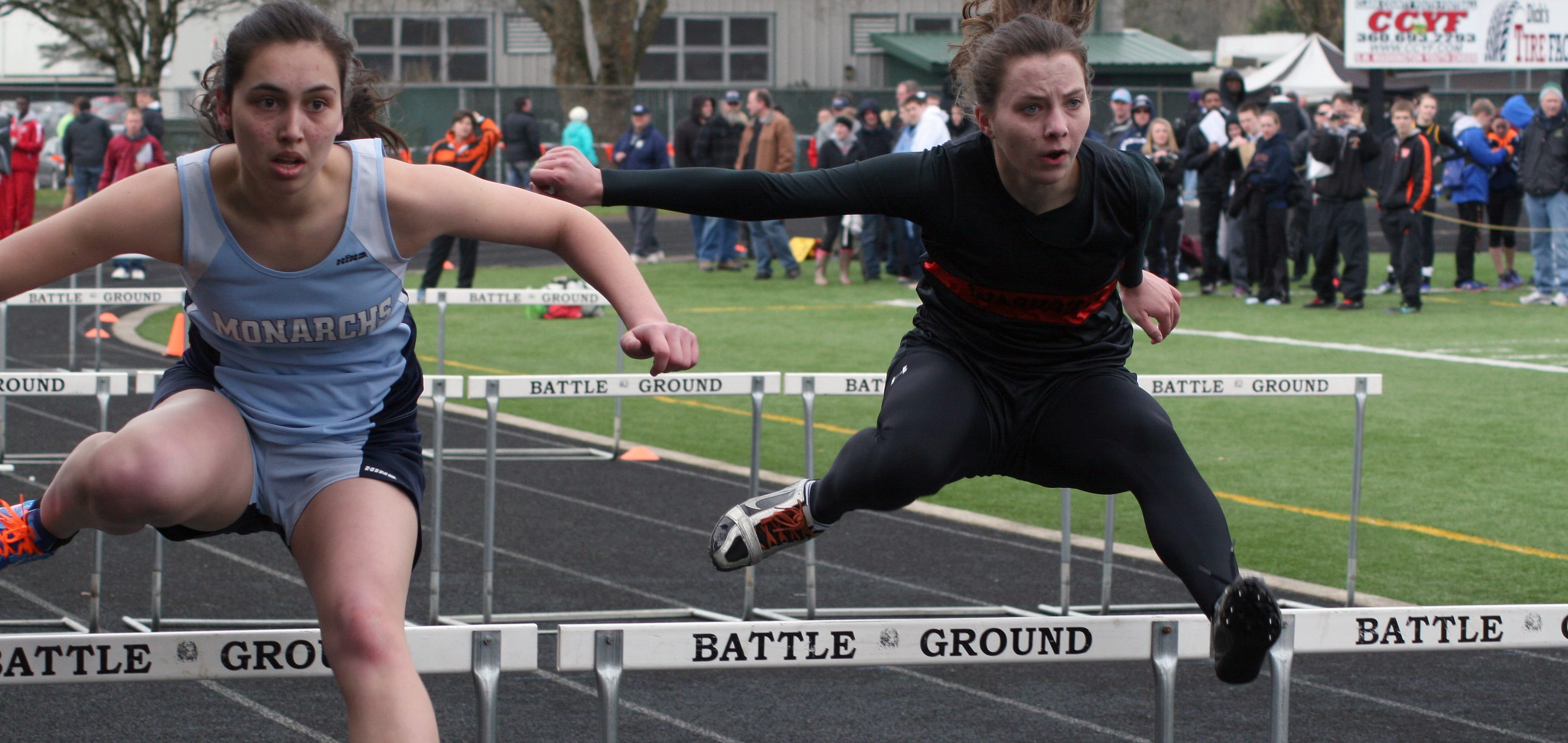 Washougal High School senior Kari Johnson (right) and a Mark Morris Monarch go toe-to-toe in the 100-meter hurdles at the Tiger Invitational Saturday, at Battle Ground High School.