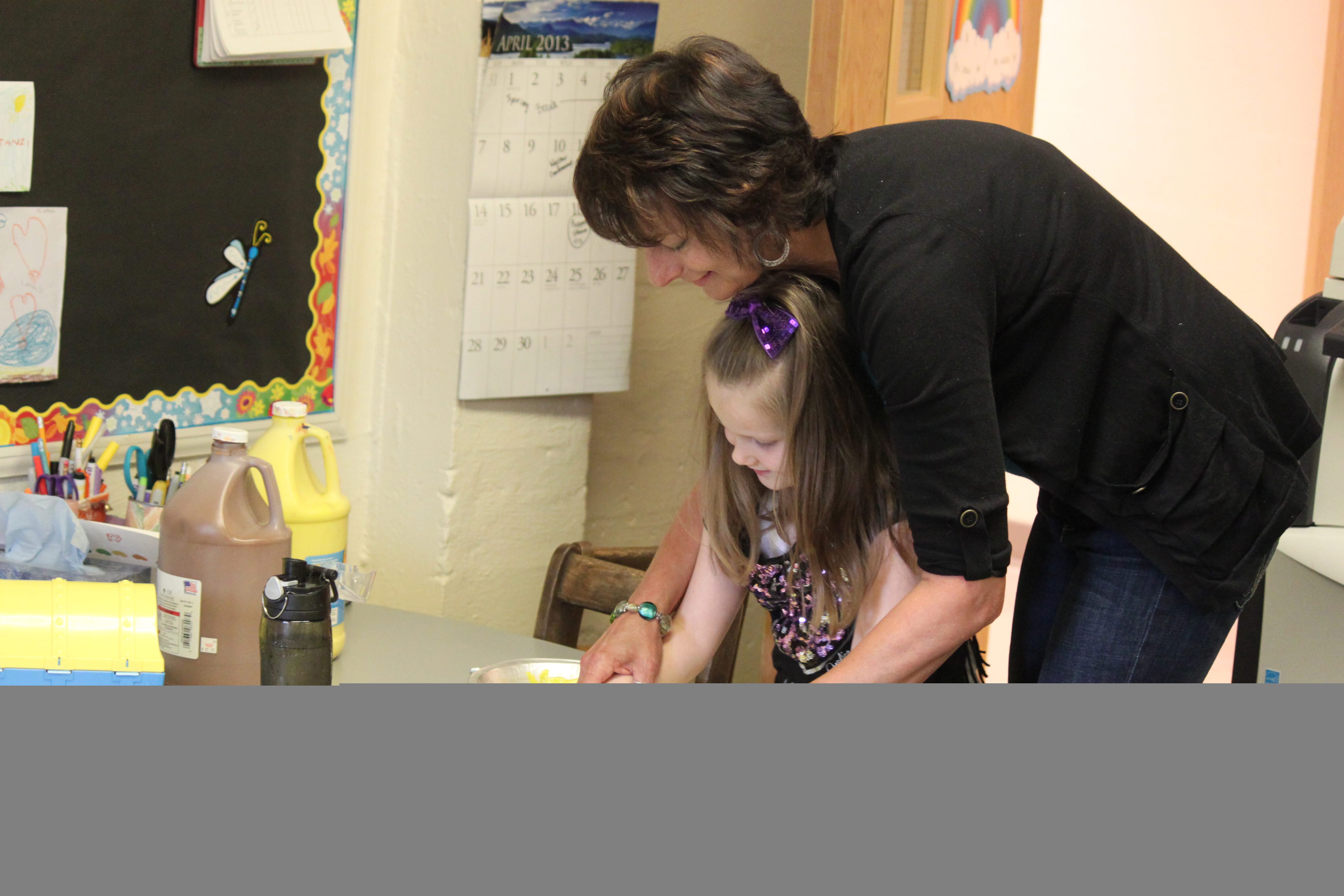 Camas-Washougal Parent Co-op Preschool teacher Maria Lattanzi helps student Fiona Robertson create a sunflower with paint. The activity was designed to complement the reading of the book, &quot;Sunflower House.&quot; After 27 years,  Lattanzi will retire on May 22 to pursue a career in social work. &quot;Maria truly cares for each and every student's well being,&quot; said Kara Prynne, a member of the preschool's executive board.