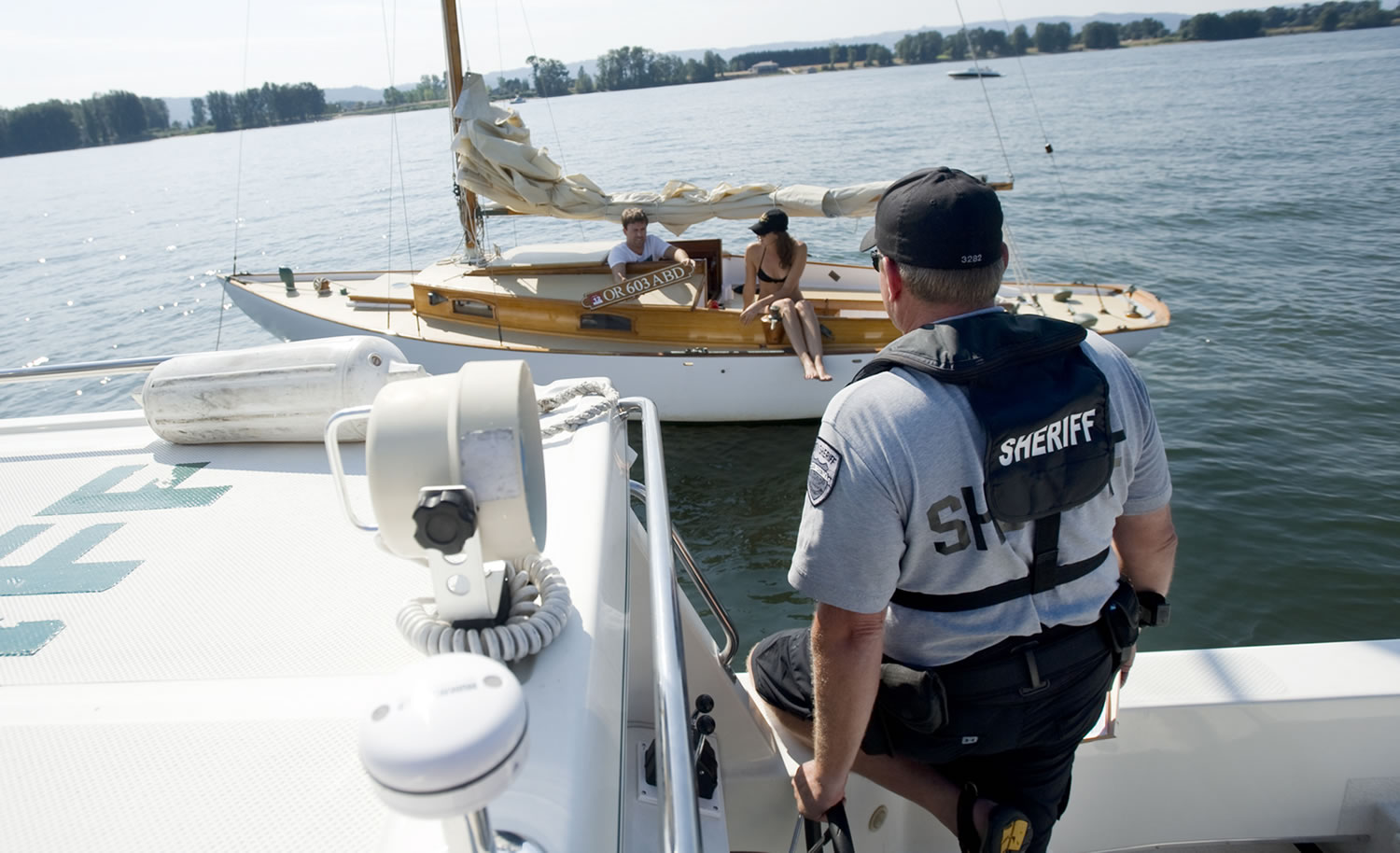 Clark County Sheriff's Deputy Todd Baker talks with boaters in August 2011 about missing registration numbers on a sailboat they were using for the day.