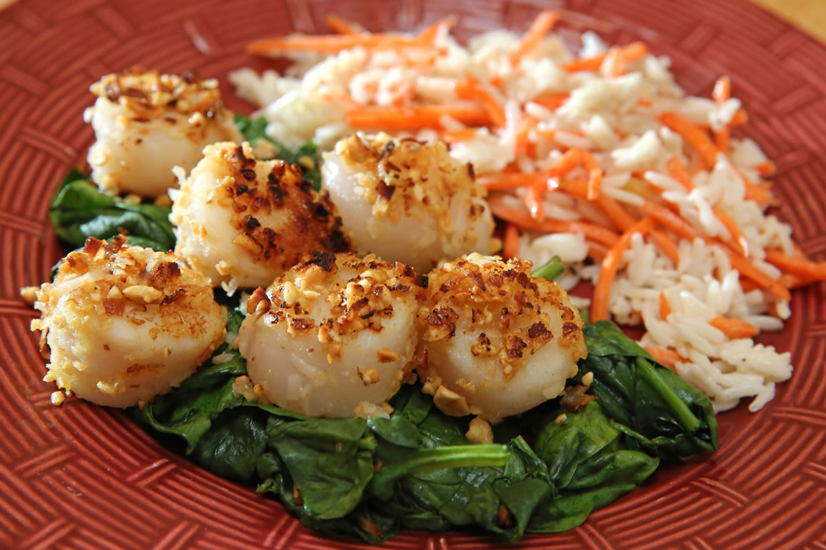 Peanut-crusted scallops with coconut-carrot rice topped on bed of spinach make for a quick meal.