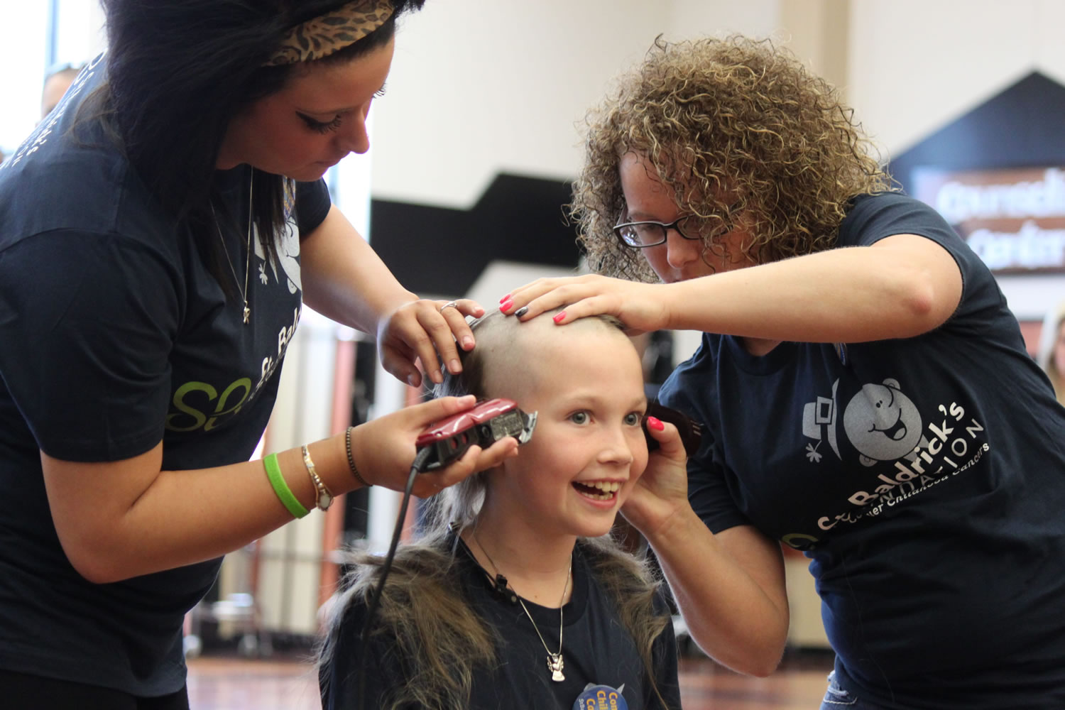 Washougal third-grader and cancer survivor Sammy Mederos reacts to getting her long locks of curly hair shaved off during a fundraiser for St. Baldrick's Foundation this afternoon at Washougal High School. Mederos was diagnosed with leukemia when she was in kindergarten. Mederos and her family helped organize the event, which included participation by Washougal Mayor Sean Guard and Cape Horn-Skye Elementary School secretary Mary La France--a breast cancer survivor.
