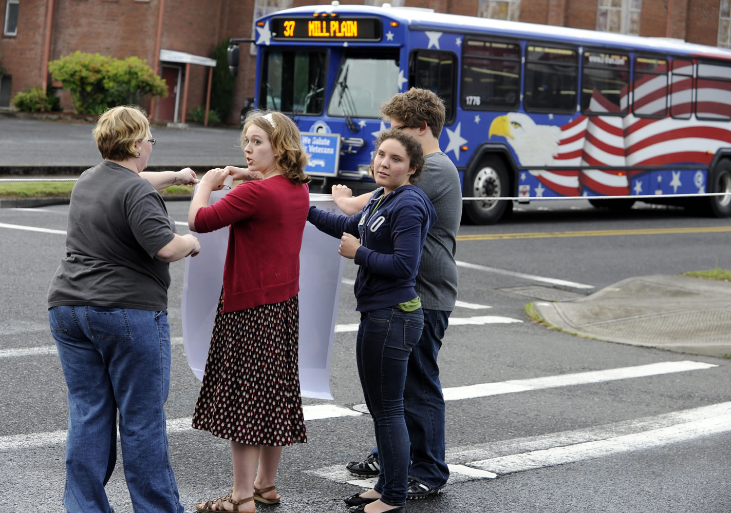 Brooklyn Newcomb, second left, the sister of Benjamin Fulwiler, assisted by Jennie Stanavech, left, blocks a C-Tran bus with a rope during a vigil on what would have been his 12th birthday.