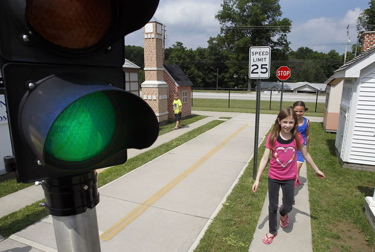 Paul Tople/Akron Beacon Journal
Nickolas Fenwick, 6, far left, his sister Madison Fenwick, 9, and Alyssa Walter, 8, right, practice following the sidewalk and traffic safety rules as they learn the safe way to walk to school at the Safety Village Playground at the Stow, Ohio, Fire Department.