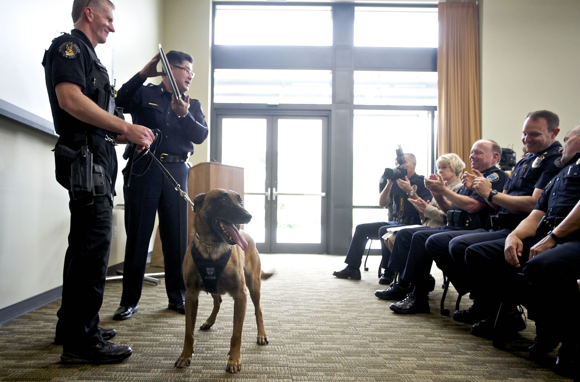 The Vancouver Police Chief Cliff Cook holds up a plaque as he recognizes officer Jack Anderson, left, and his K-9 partner, Ike, during a ceremony June 25.