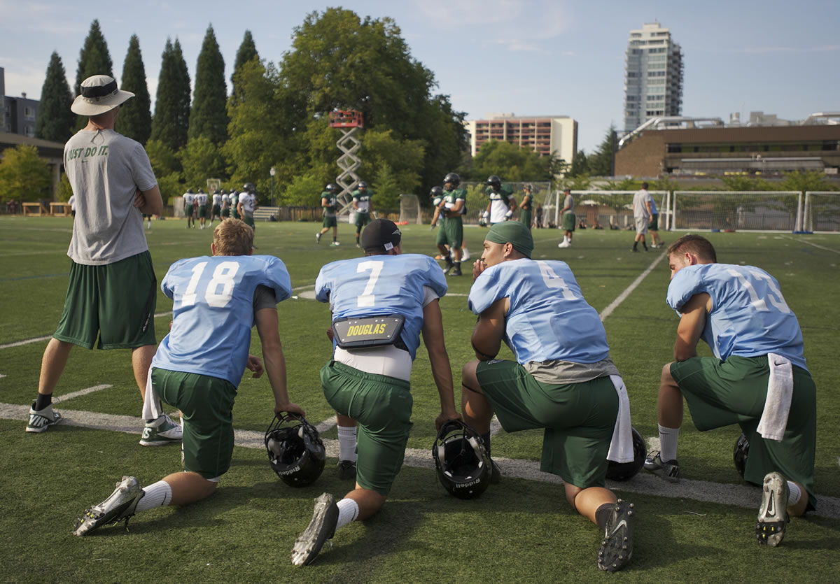 Kieran McDonagh, second from right, kneels on the sideline with other quarterbacks during practice at Portland State University on Wednesday.