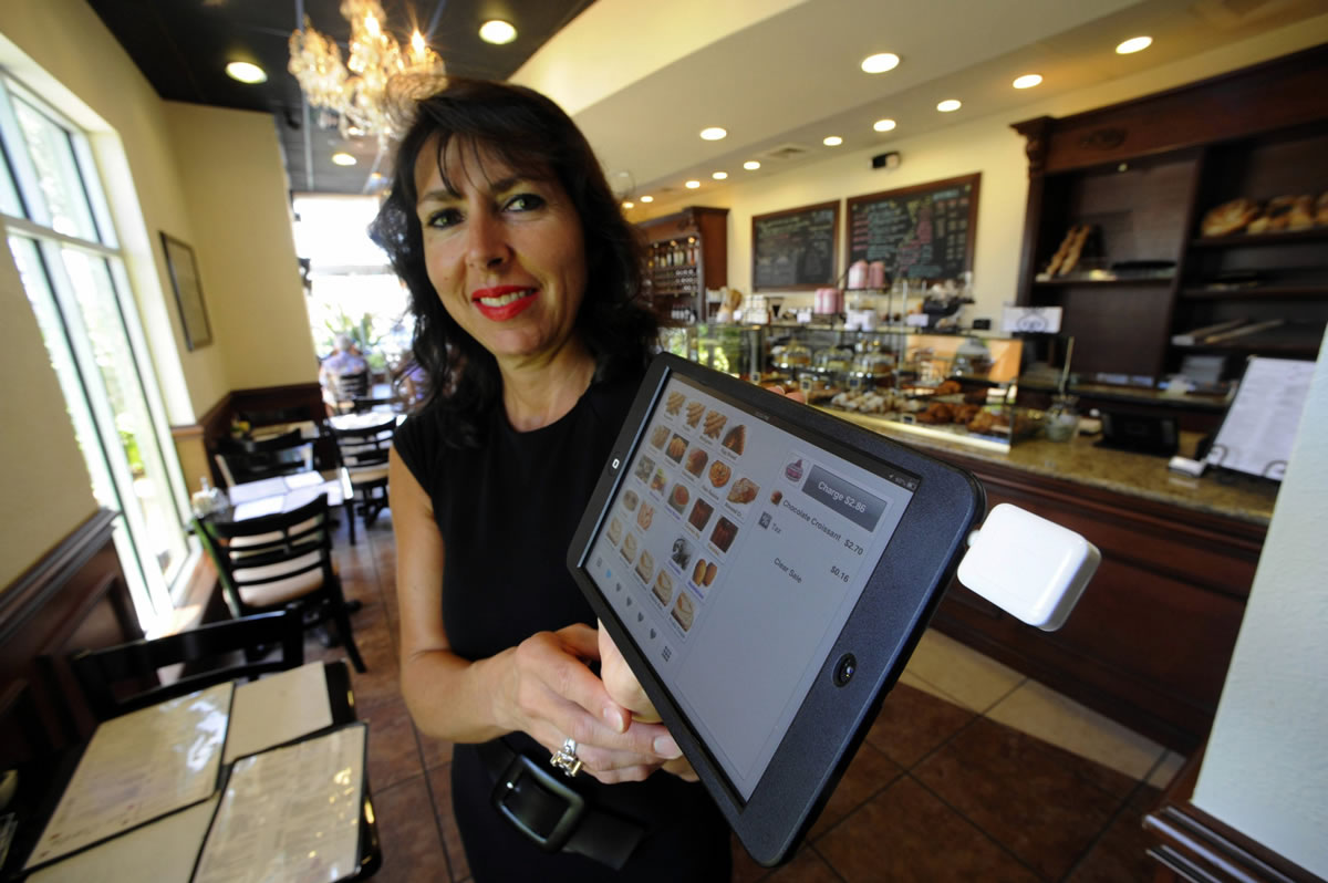 Marie Jose Brau, owner of the Bakery of France in Boca Raton, Fla., displays one of the iPad minis equipped with a Square credit card reader that her servers deliver to diners.