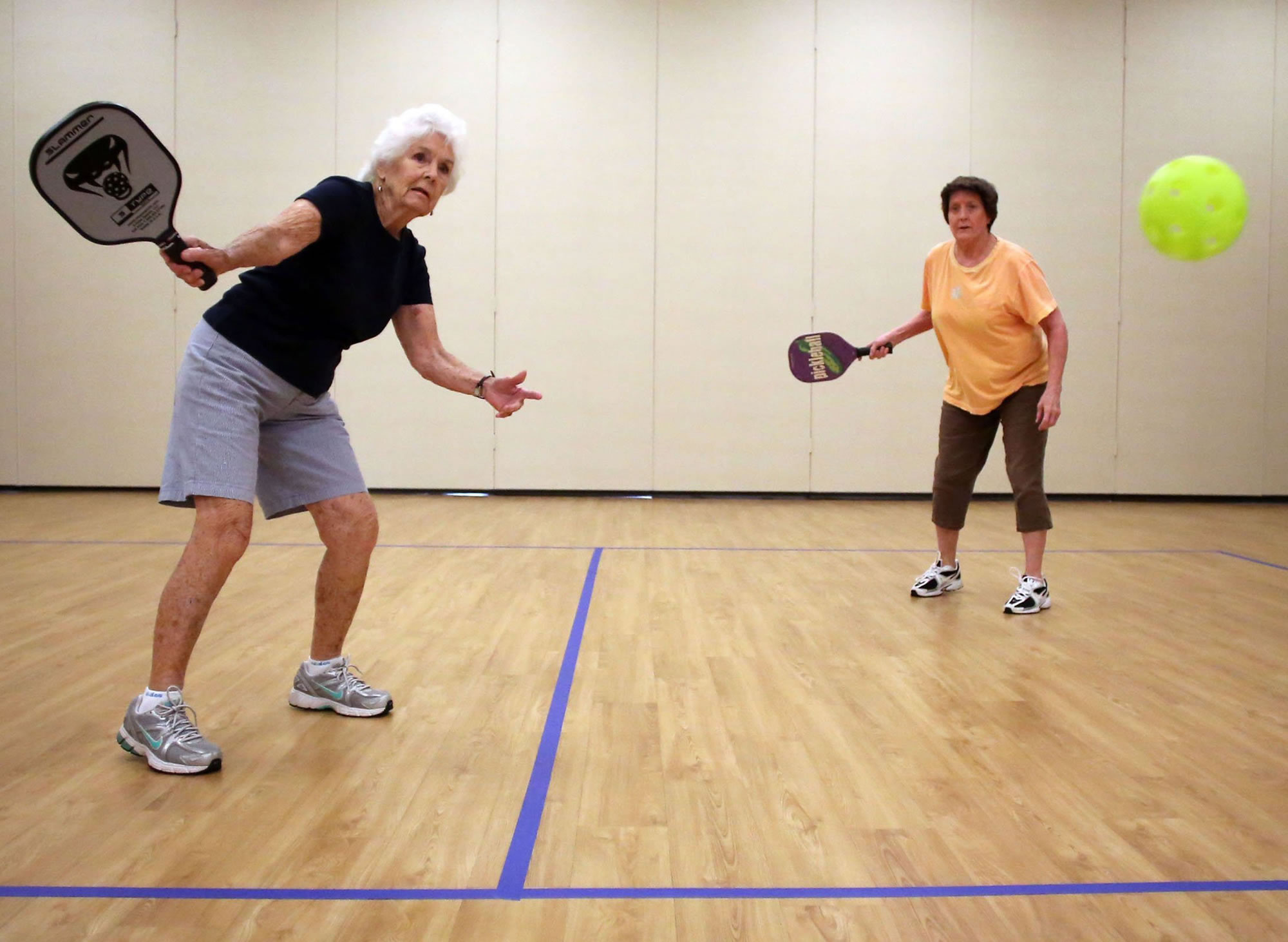 Jay Massey, left, returns a volley as her teammate Betty Bailey watches as they play pickleball Aug.