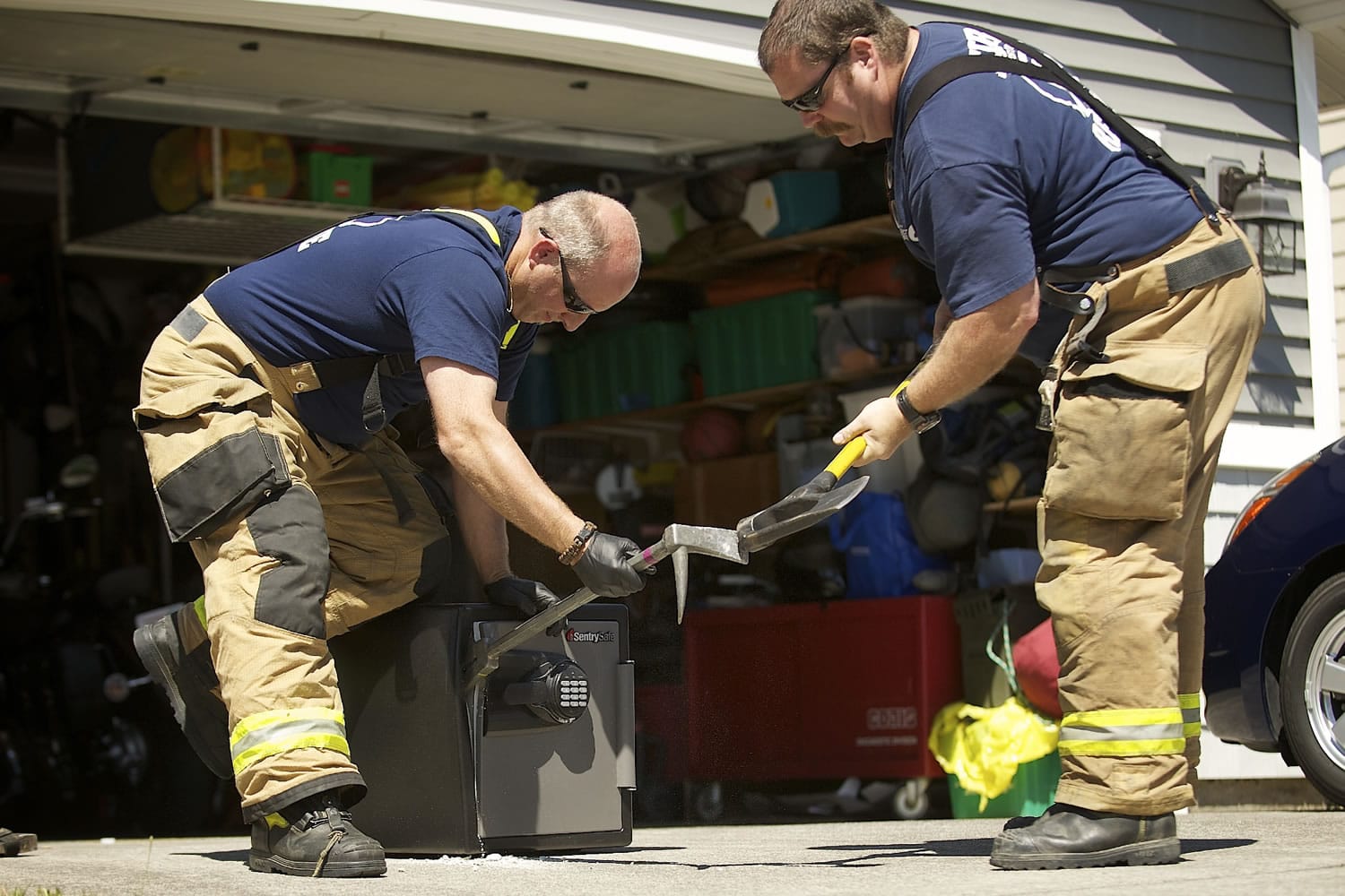 Clark County Fire District 6 firefighters David Fisher, left, and Darren Bush force open a safe July 24 for the Clark-Vancouver Drug Task Force in a search for evidence at the home of a suspected drug dealer.