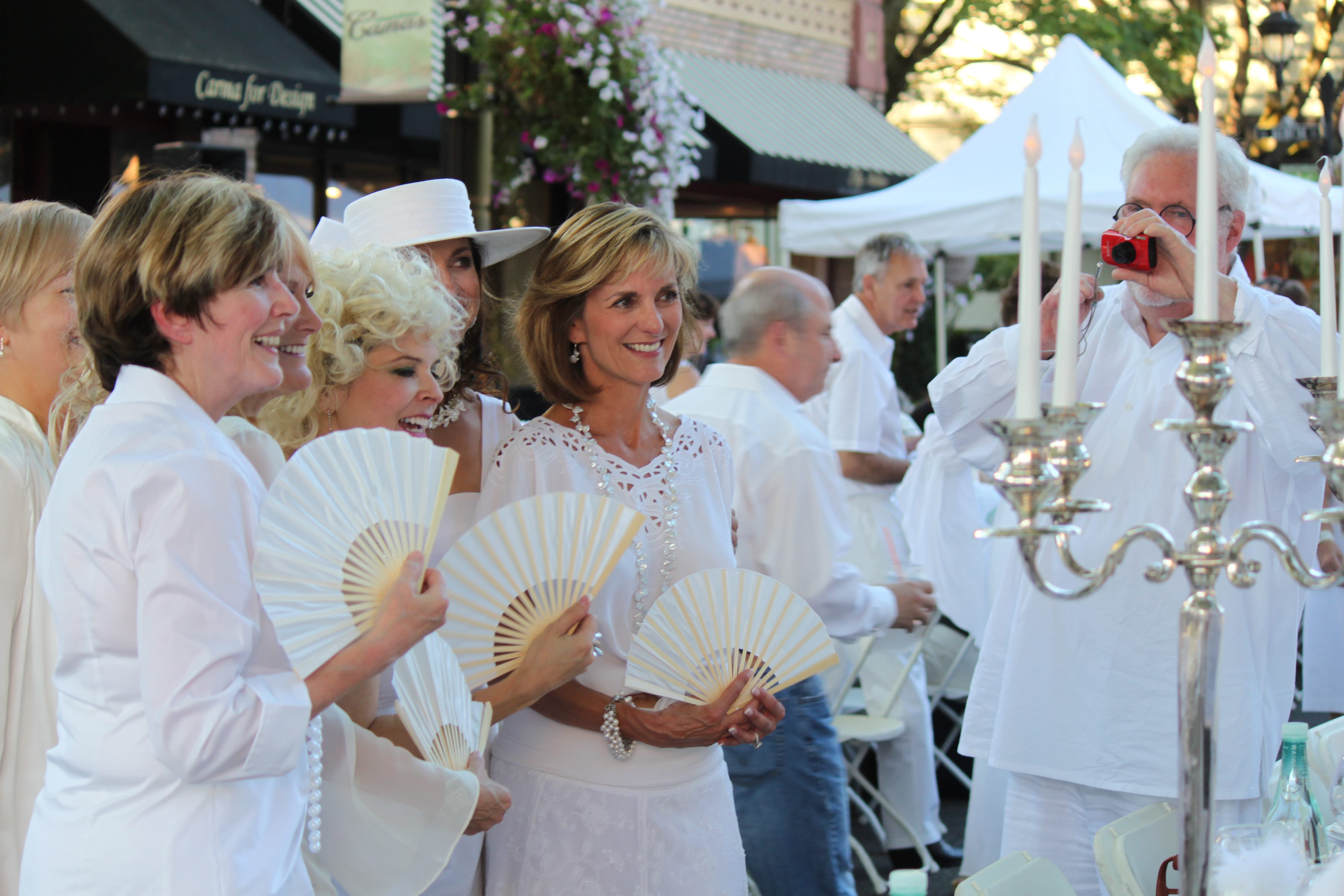 More than 150 people attended the &quot;Camas in White, Dinner on Fourth Avenue&quot; event on Saturday evening in downtown. Attendees dressed in white outfits and dined at tables decorated in white color themes. This group of friends, many of whom are neighbors in the Lacamas Shores area, pose for pictures before dinner begins. The event was a fundraiser for the Camas-Washougal Mural Project. Through an auction of five art pieces, approximately $2,215 was raised, including a $1,400 winning bid by Capstone Technology Corp. for a  painting of the Camas mill by local artist Maria Grazia Repetto.