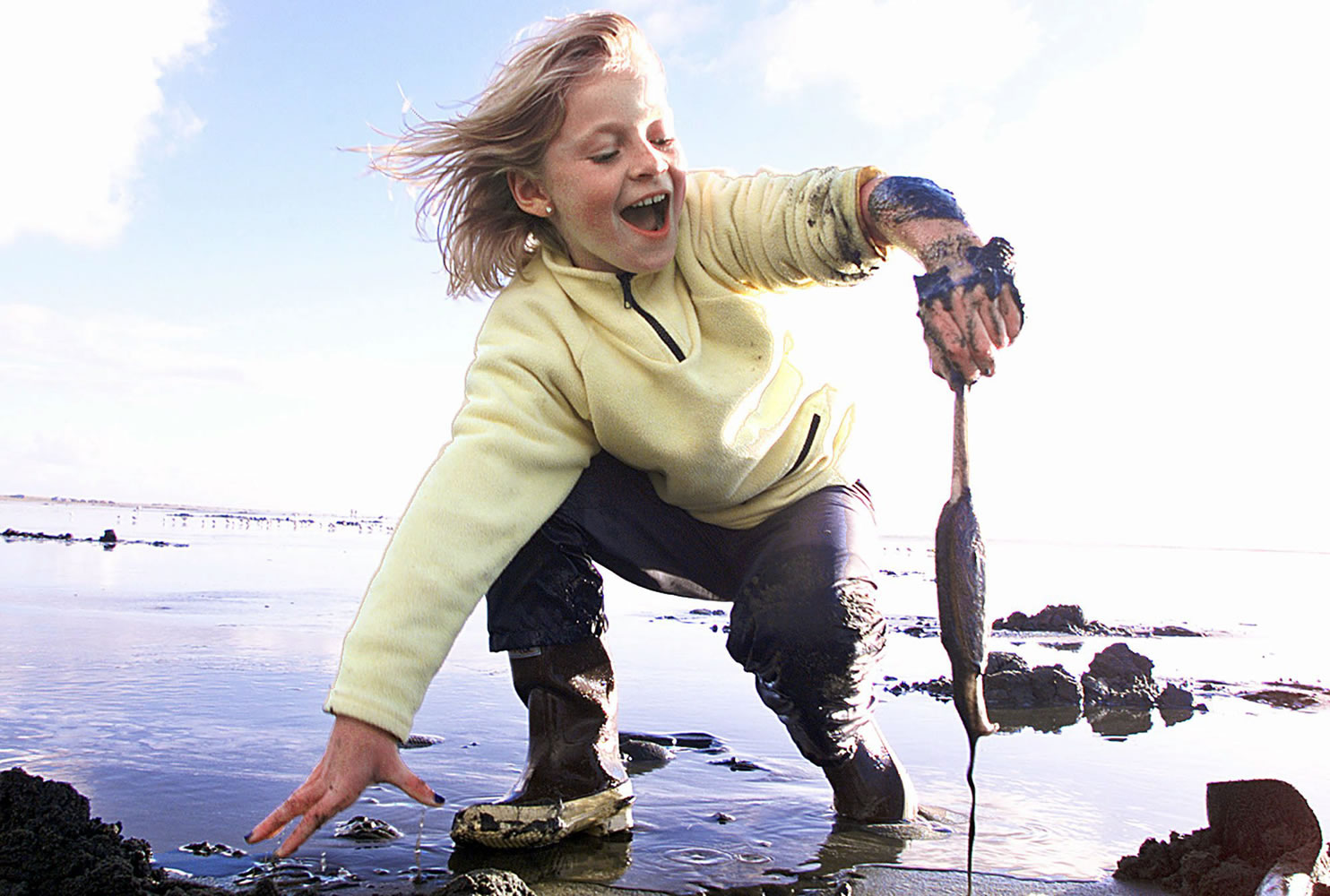 Savannah Hieronymus reacts as she pulls a slimy razor clam out of the sand in October 2001 at Ocean Shores.