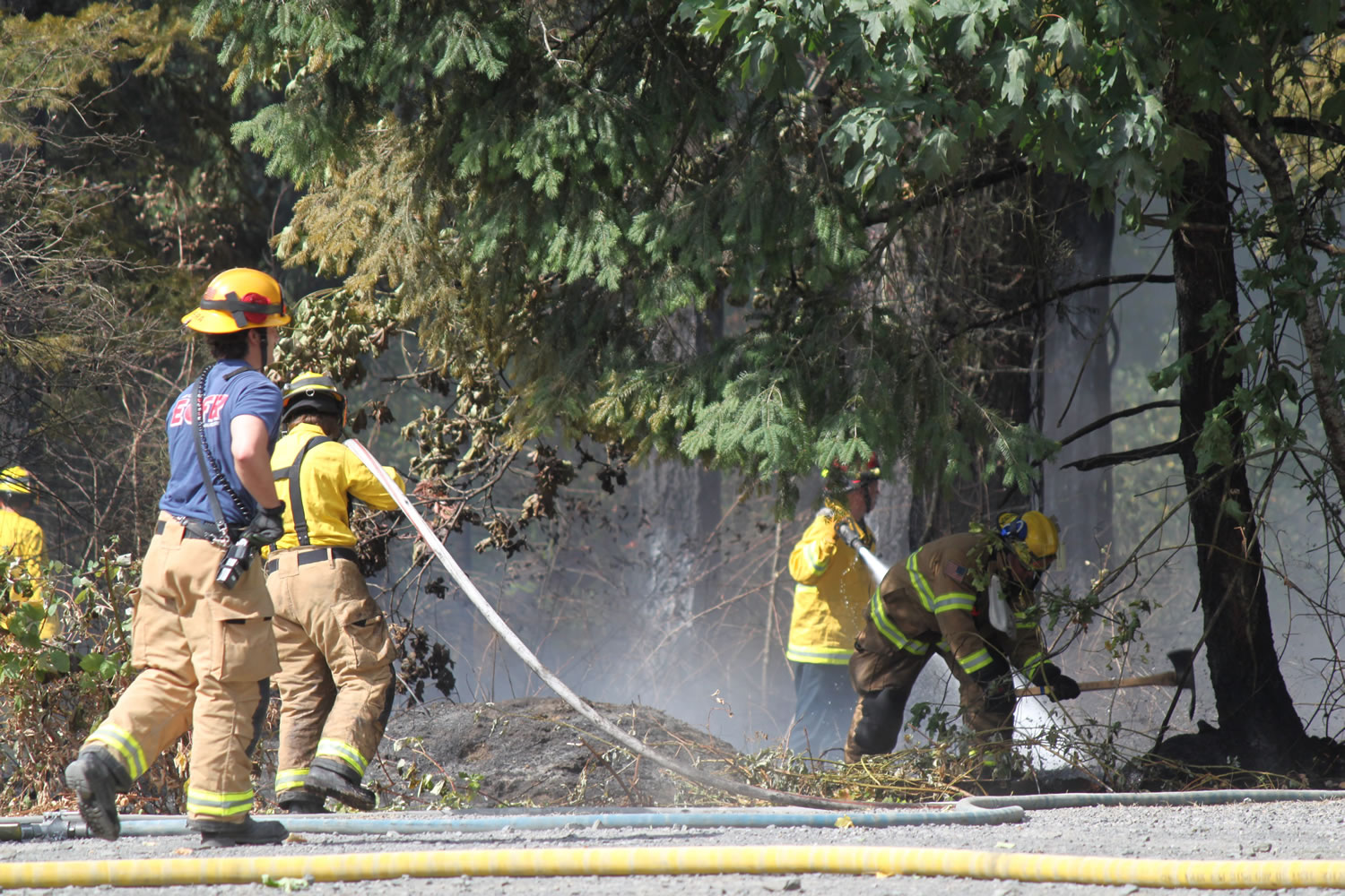 Emergency crews from three agencies work to put out a brush fire on Leadbetter Road Thursday morning.