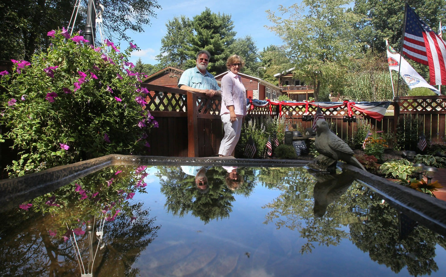Mark Pollock and Kathy Roby are reflected in a birdbath in their memory garden at their home in Suffield Township, Ohio.