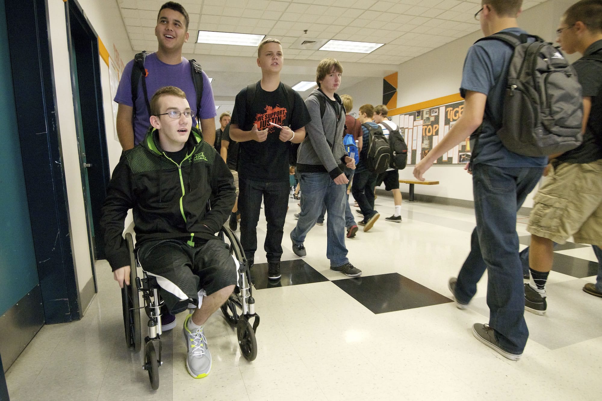 With the help of his friend Zechariah Maniar, 16, Justin Carey uses a wheelchair to make his way through the halls of Battle Ground High School on the first day of school Wednesday.