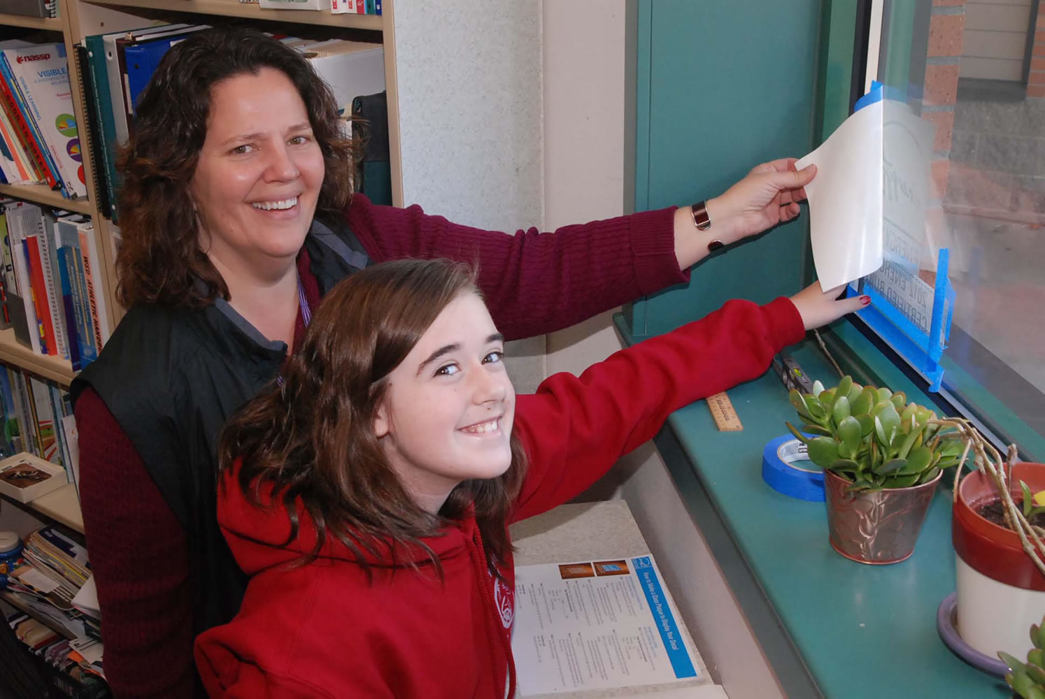 Sandi Christensen, Canyon Creek Middle School principal, and seventh-grader Natalie Garner proudly display the Energy Star decal earned as a result of energy improvements at the school.