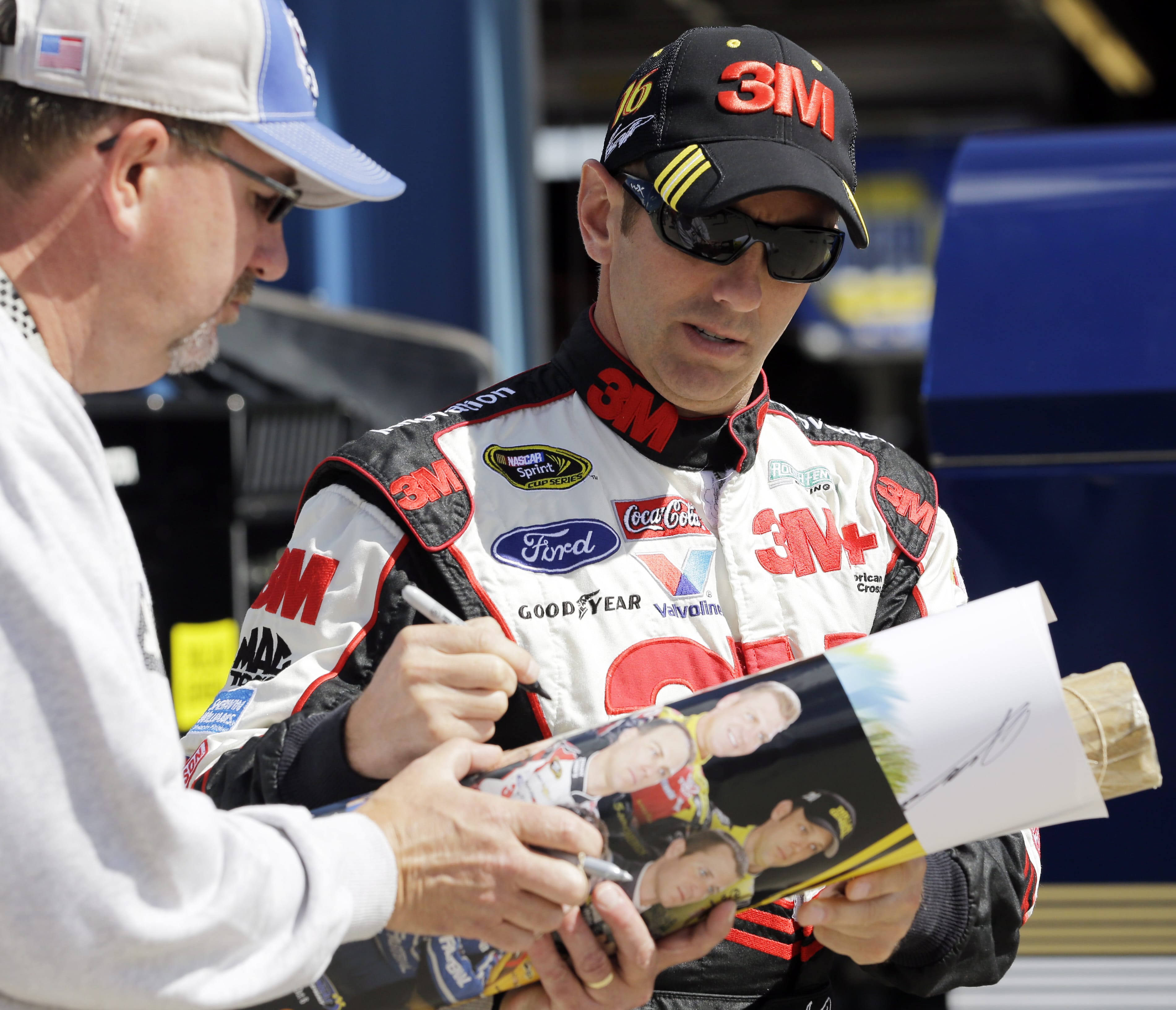 Driver Greg Biffle, right, signs an autograph for a fan as he walks to his garage during practice for Sunday's NASCAR Sprint Cup Series auto race at Chicagoland Speedway in Joliet, Ill., Friday, Sept. 13, 2013. (AP Photo/Nam Y.