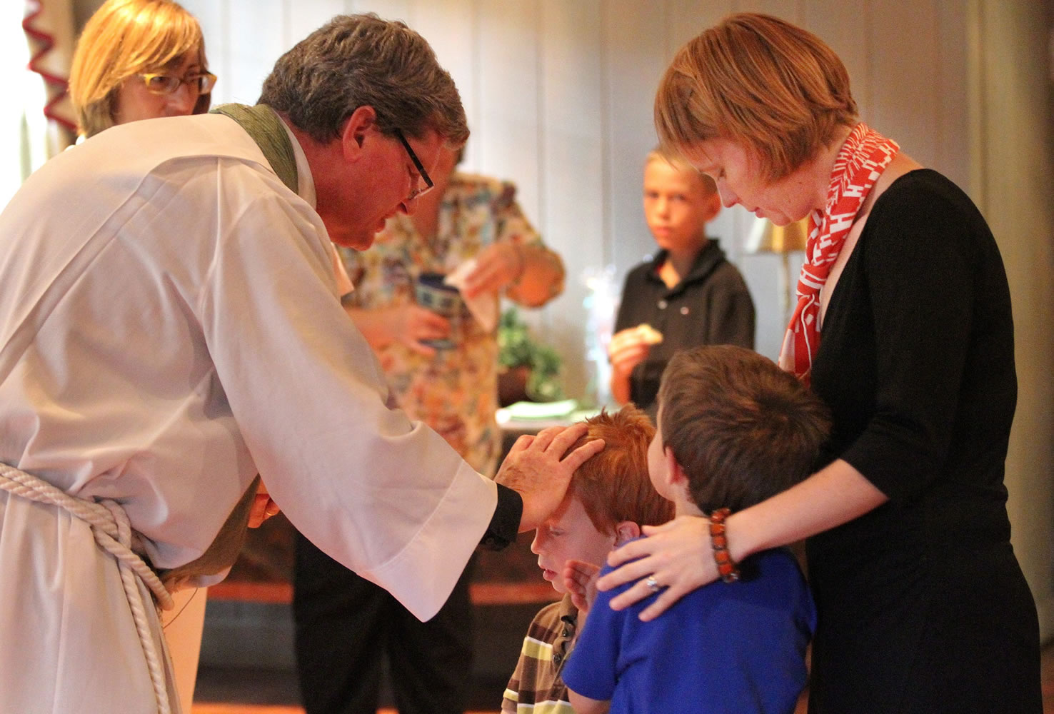 The Rev. Chip Stokes bestows a blessing on Thomas Barken-Stewart, 3, who is with his mother, Jacqueline Barken, and brother, Joshua Barken-Stewart, at a service at St. Paul's Episcopal Church in Delray Beach, Fla.