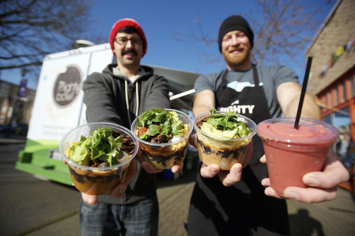 Steve Valenta, left, and Kevin DeGraw show off the Kiggins Bowl, from left, the Mighty Bowl, the Peanut Bowl and the Carter Park smoothie outside their mobile food truck.