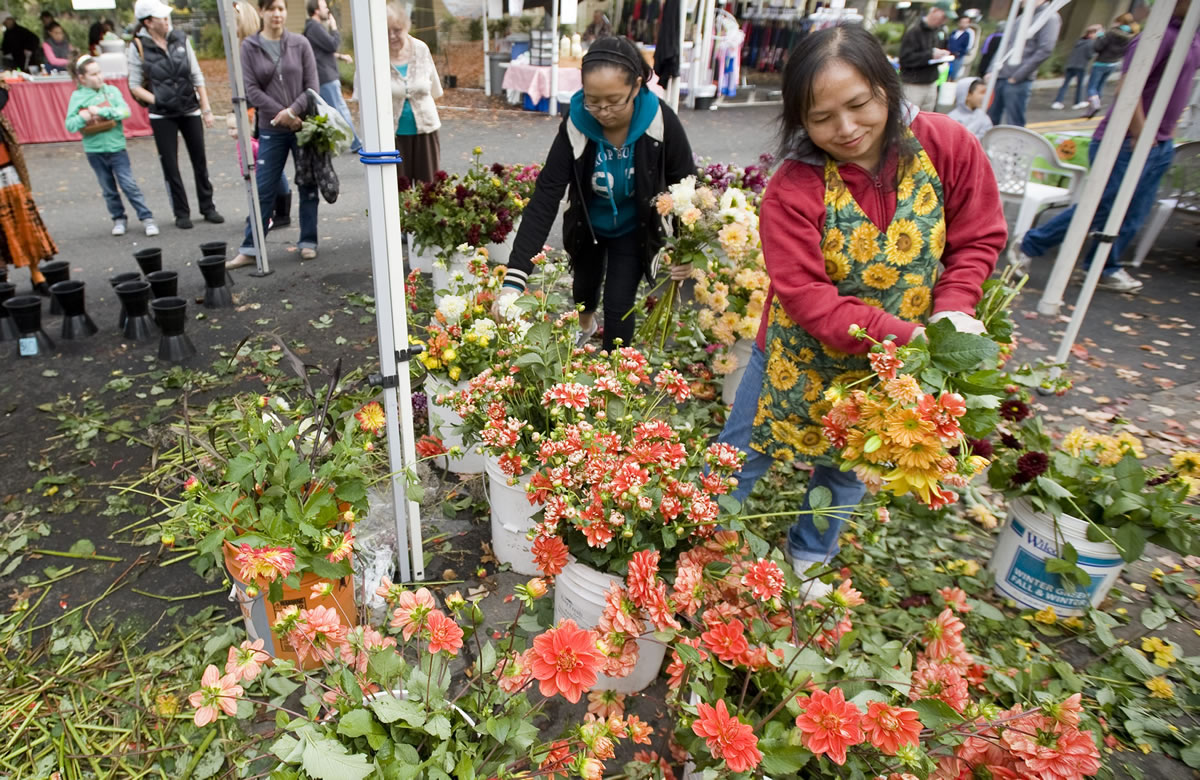 Sia Vang, right, and Pajku Cha, 15, from the Cha Meng Family Farm, arrange flowers on the last day of the 2010 Vancouver Farmers Market.