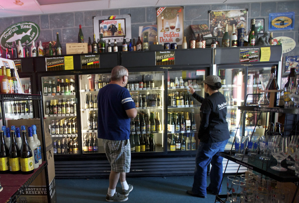 By The Bottle owner Arlene Nunez, right, helps a customer pick out beer in August.