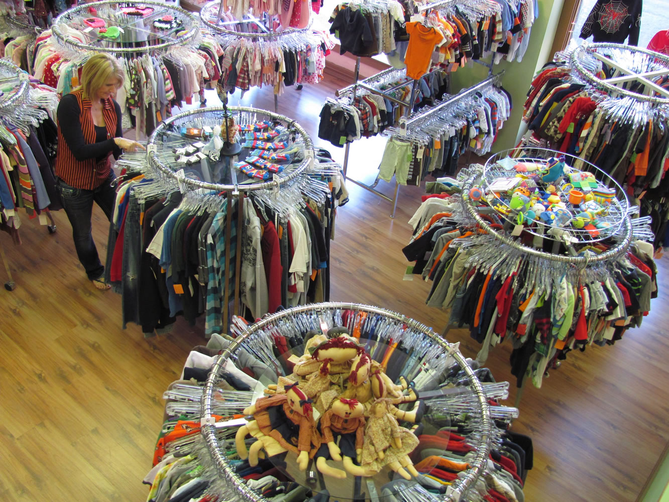 Robin Simonds, manager of Lil' Dudes and Divas, arranges racks of &quot;gently used&quot; children's outfits in the downtown Camas shop. New clothing and accessories are displayed along the walls. Toys, games and baby strollers are also available, and there are handcrafted items made by area crafters. Art classes for toddlers will be offered, starting in November.