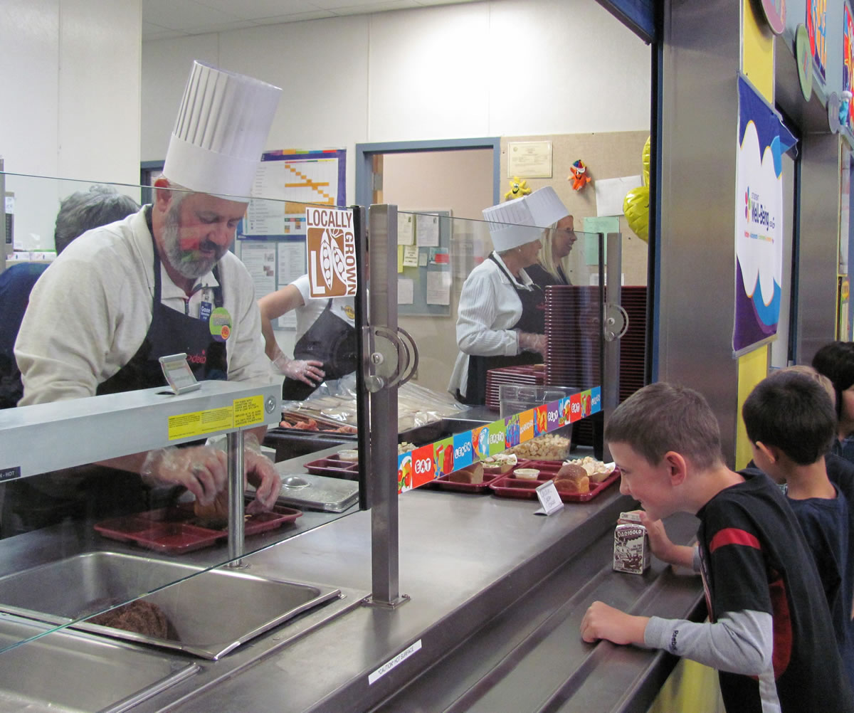 Washougal Mayor Sean Guard serves lunch to children at Gause Elementary School in celebration of National School Lunch Week.