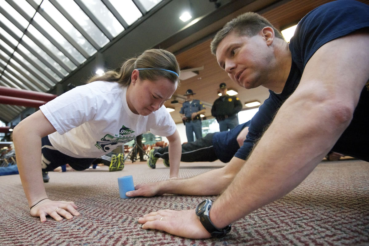 Vancouver native Alyssa Beauchamp, 22, completes a push-up test during Washington State Patrol's open cadet testing event Saturday as Trooper Mike Johnson counts.