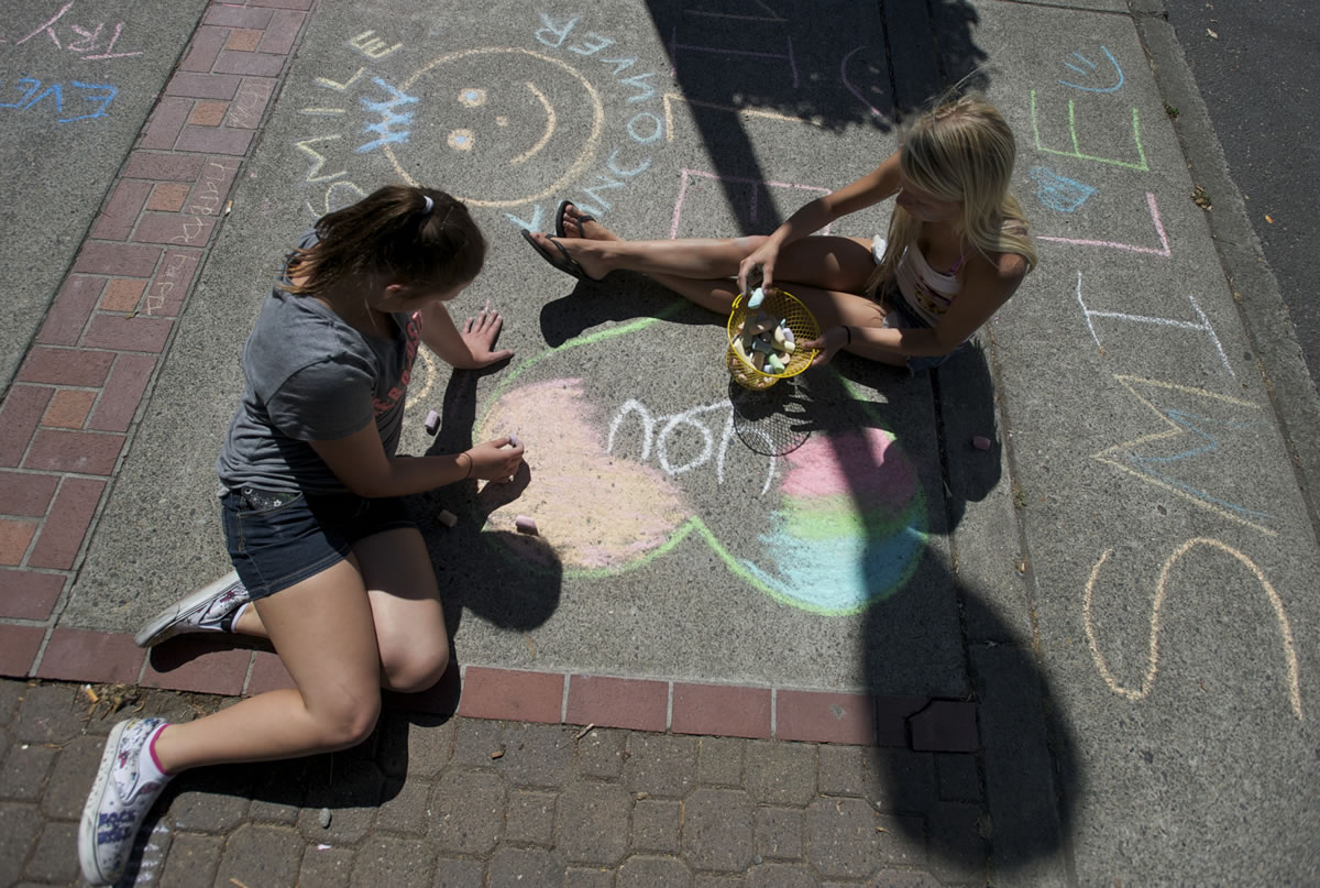 Junior Joy Team members Abigail Brooks, 12, left, and Sierra Watters, 12, were among about three dozen children who decorated the sidewalks on Main Street on Tuesday with colorful, positive pictures and messages during the third annual Chalk the Walks.