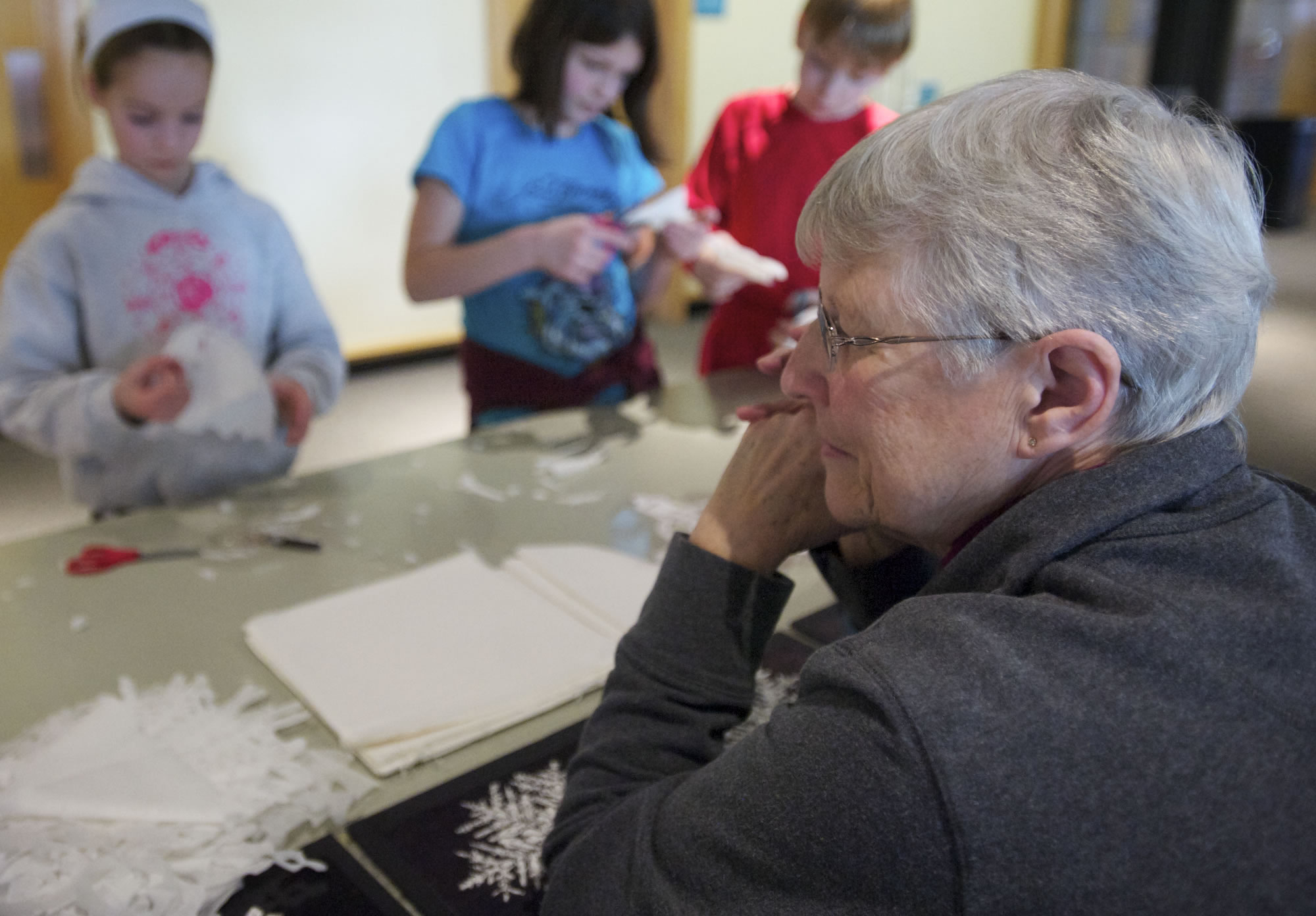 Longtime volunteer Marilyn Feddeler, 75, helps kids make snowflakes out of tissue paper at the Water Resources Education Center's Second Saturday event.