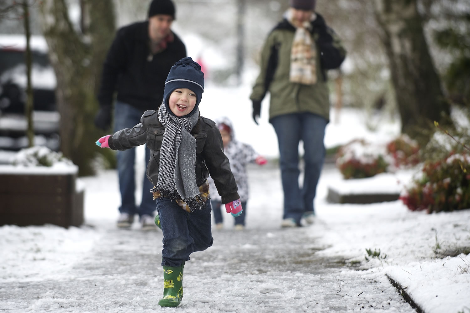 Nolan Bain, 3, frolics in the snow on a morning walk March 22 with his family -- Brian Bain, left, Aurora, 16 months, and Kirby Bain -- in the Lincoln neighborhood of Vancouver.