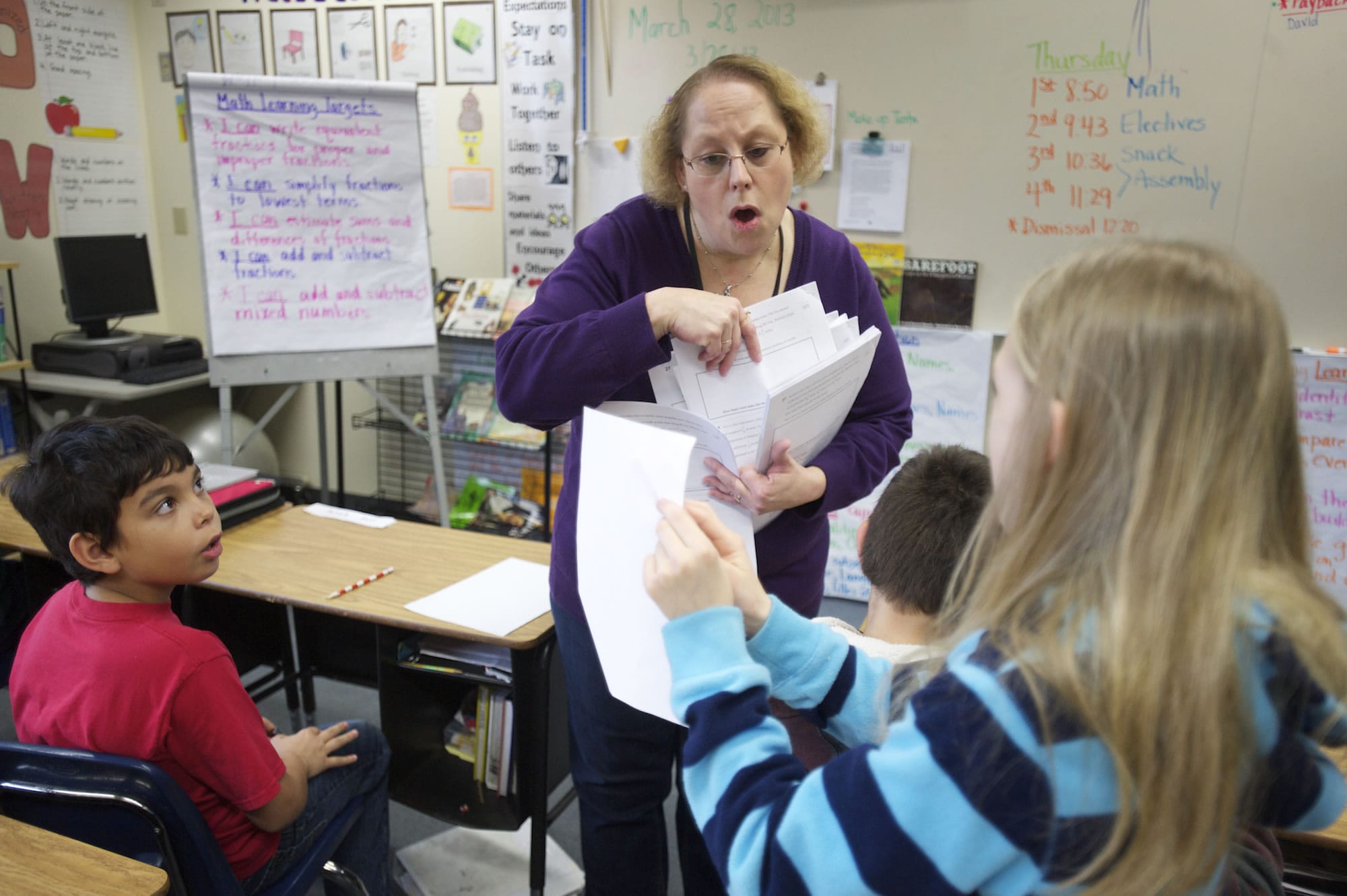 Eileen O'Connor, a fifth-grade teacher at Maple Grove K-8 school, distributes papers to her students the day before spring break. On Feb. 12, Battle Ground was the only school district of 41 in the state that saw its maintenance and operation levy fail.