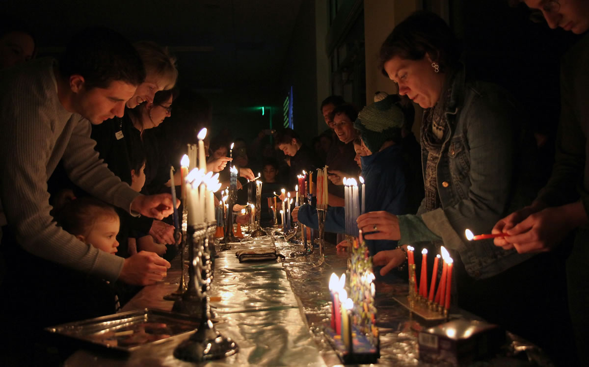 Members of Congregation Kol Ami, including Lauren Trexler, at right, light candles on menorahs Sunday evening to celebrate Hanukkah.