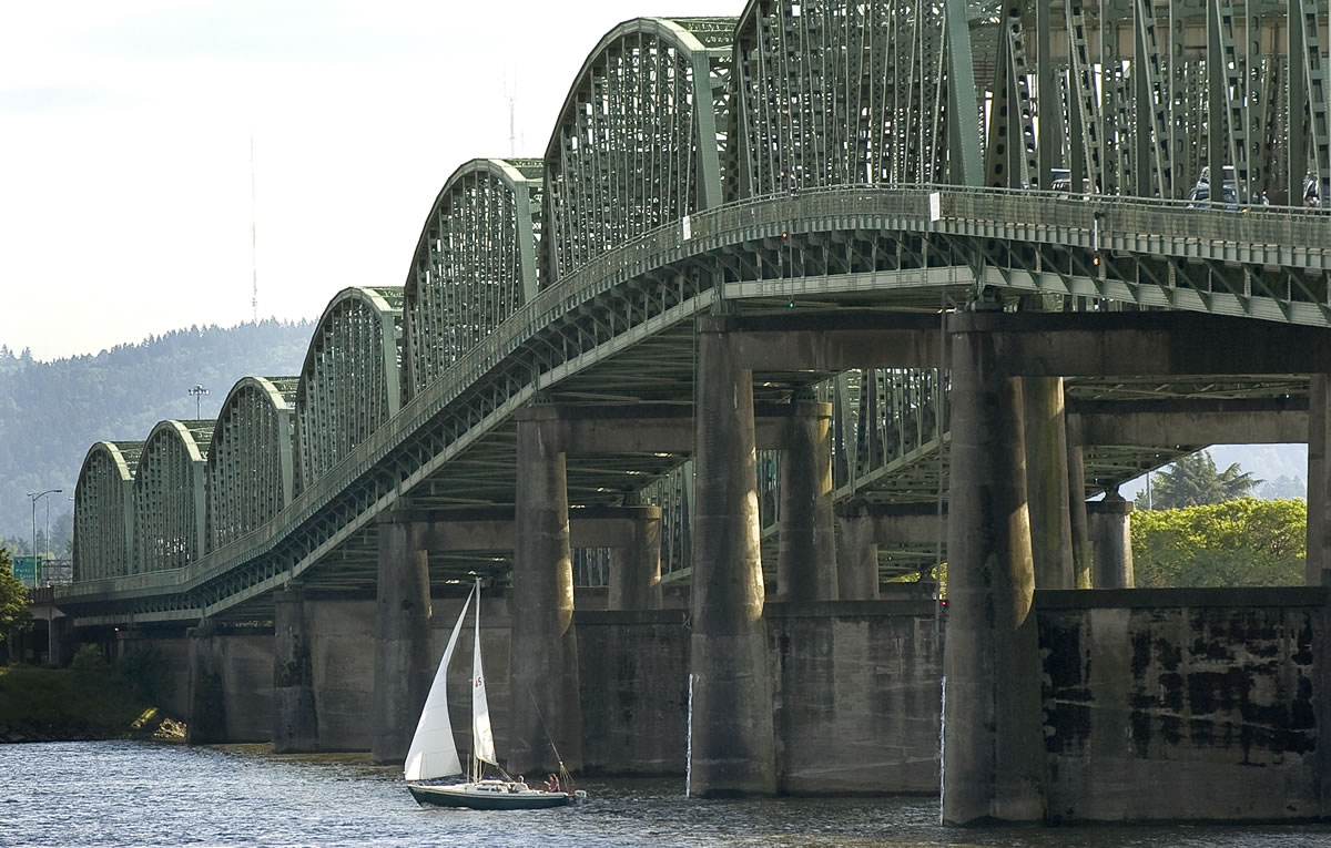 A sailboat passes under the Interstate 5 Bridge.