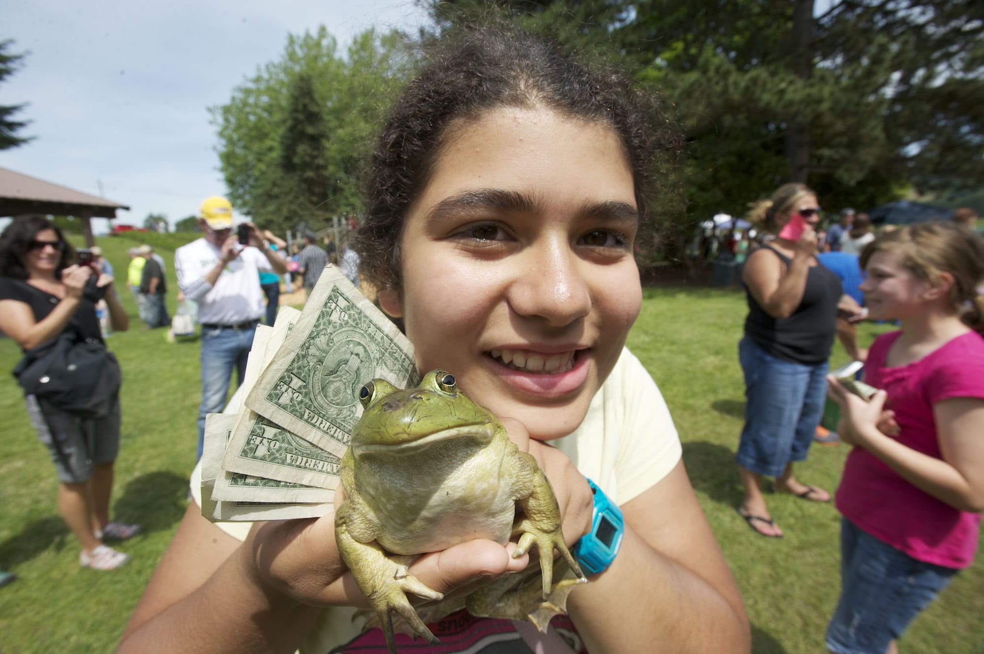 Sahara Jones, of Vancouver, poses for a photo with a loaner frog at the 46th Annual Frog Jump contest at Woodland Planters Days Saturday.
