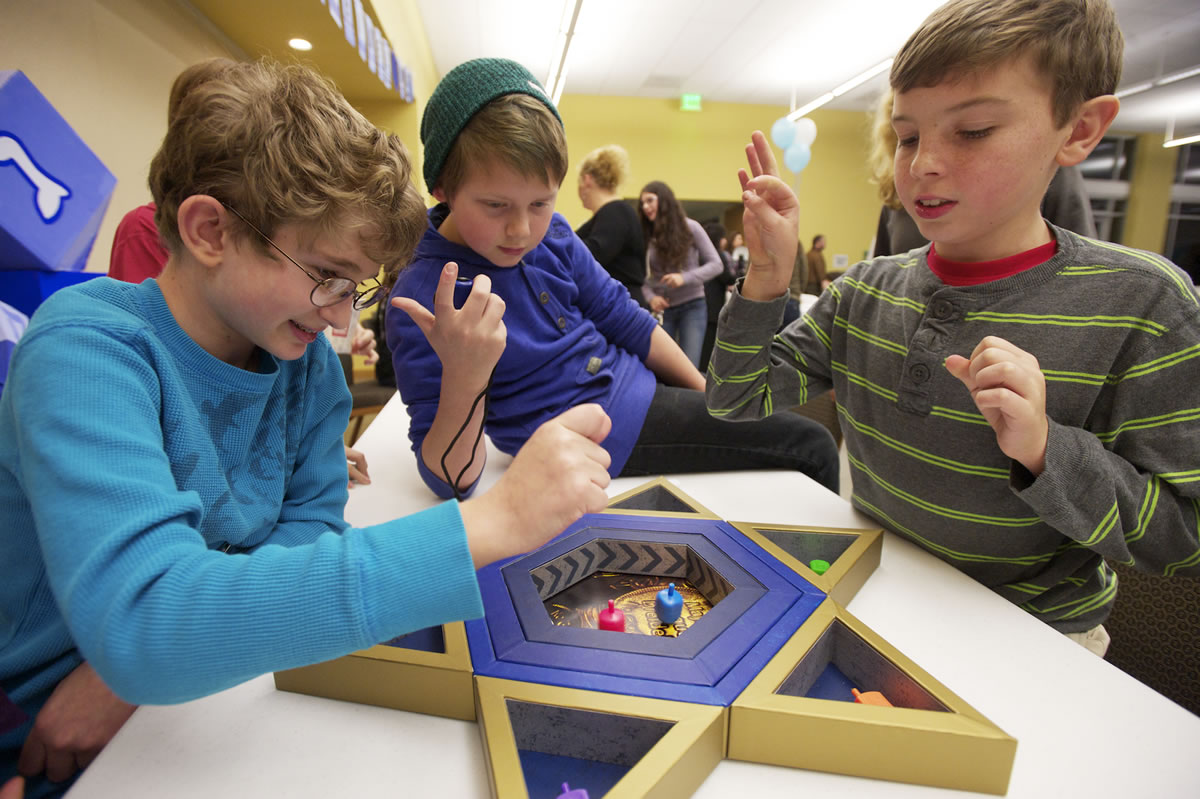 Will Higgins, 11, from left, Asher Herrmann, 11, and Connor Finks, 12, play a dreidel game at a Congregation Kol Ami's Hanukkah celebration on Sunday.